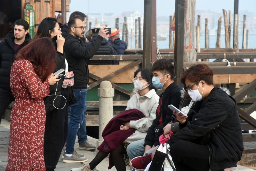 Tourists wearing protective masks visit Venice on Feb. 25, 2020, during the usual period of Carnival festivities which were cancelled due to a coronavirus outbreak in northern Italy. (Credit: Andrea Pattaro / AFP / Getty Images)