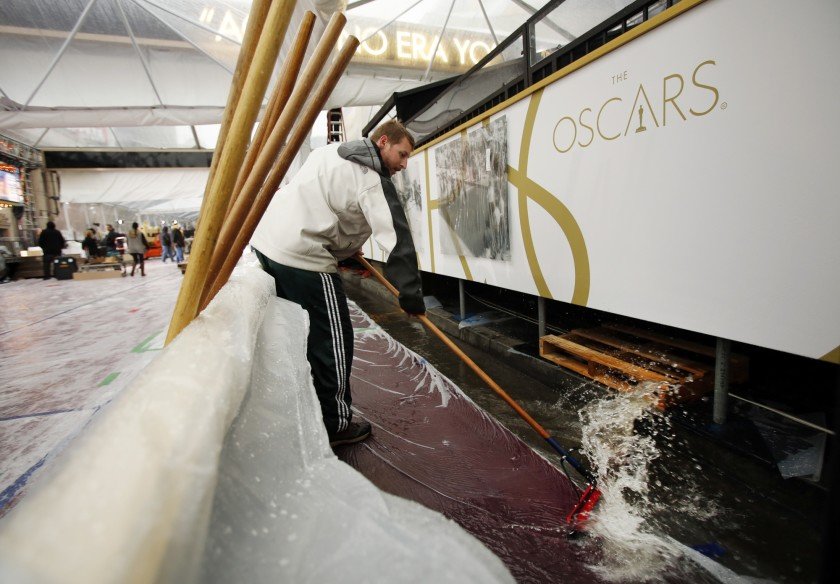 In 2014, a worker tries to clears the Oscars red carpet of rainwater outside the Dolby Theater in Hollywood. (Credit: Al Seib / Los Angeles Times)