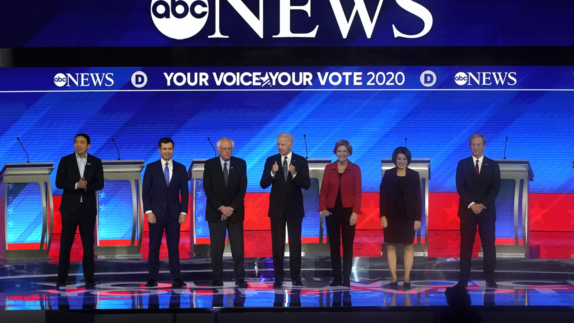 From left: Democratic presidential hopefuls Andrew Yang, Pete Buttigieg, Sen. Bernie Sanders, former Vice President Joe Biden, Sen. Elizabeth Warren, Sen. Amy Klobuchar and Tom Steyer arrive onstage for the eighth Democratic primary debate of the 2020 presidential campaign season at St. Anselm College in Manchester, New Hampshire, on Feb. 7, 2020. (Credit: Timothy A. Clary / AFP / Getty Images)