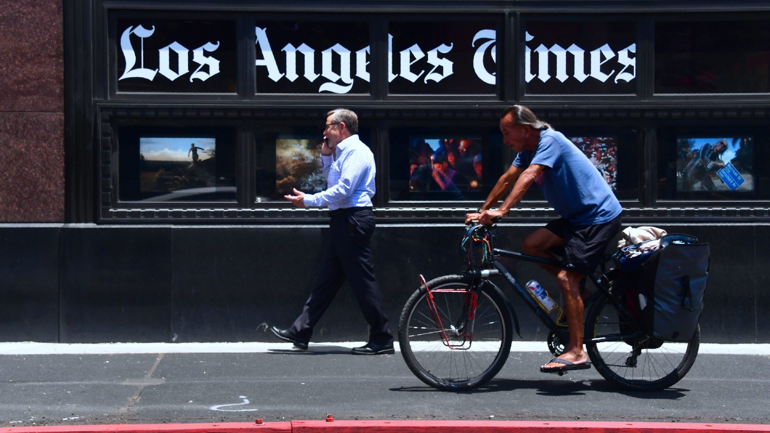 People make their way past the Los Angeles Times office building in downtown Los Angeles on July 16, 2018. (Credit: FREDERIC J. BROWN/AFP via Getty Images)