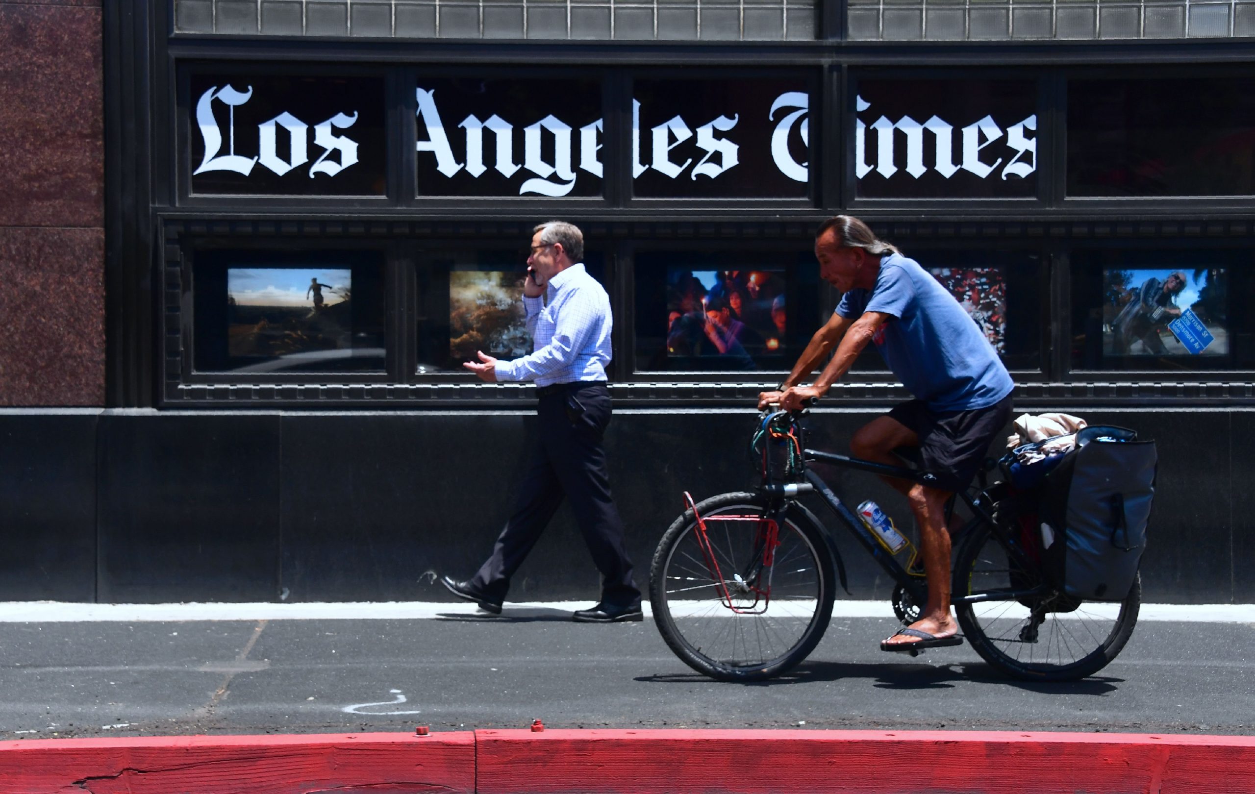 People make their way past the Los Angeles Times office building in downtown Los Angeles on July 16, 2018. (Credit: FREDERIC J. BROWN/AFP via Getty Images)