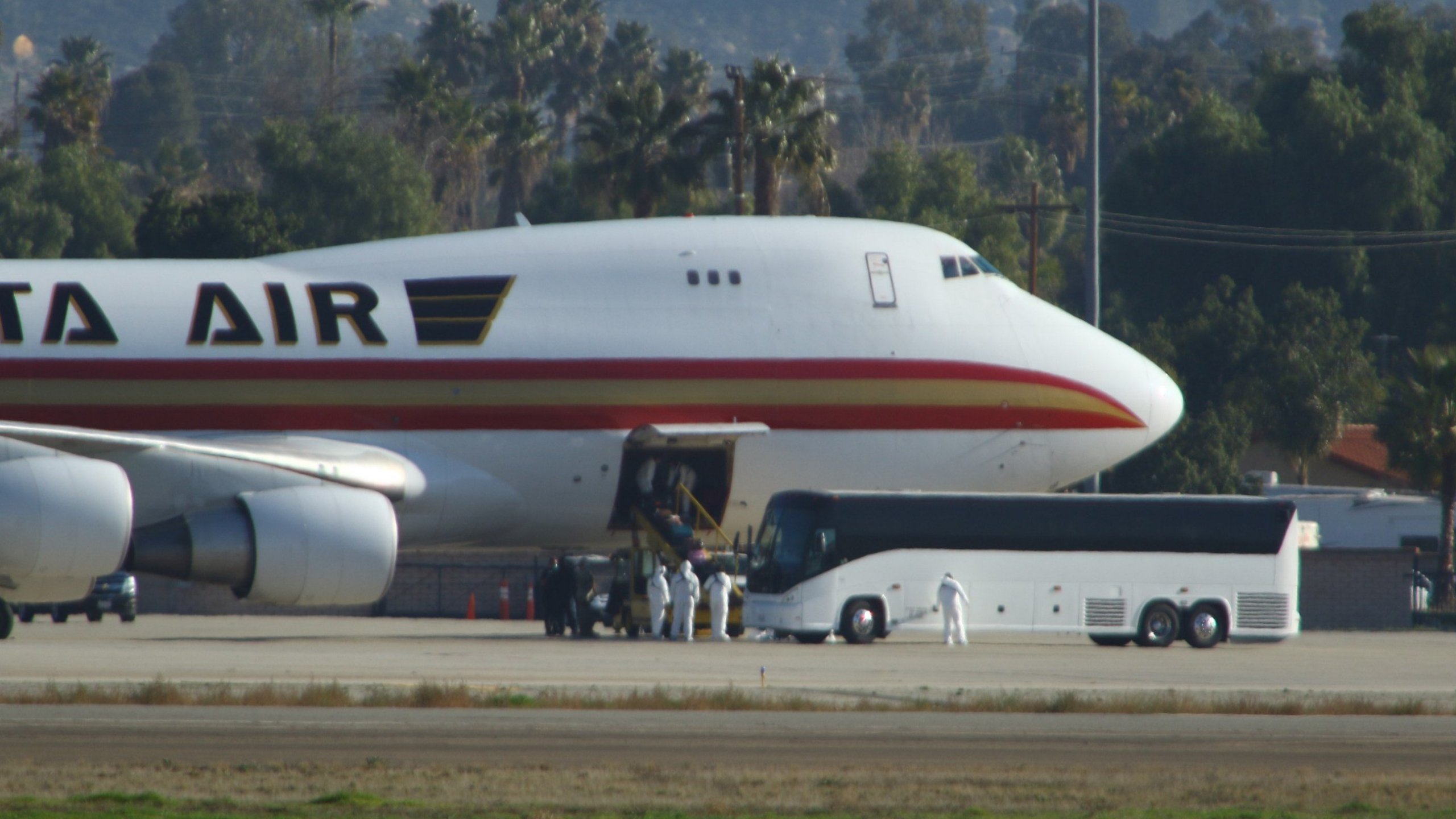 Personnel in biological hazard suits welcome passengers evacuated from Wuhan, the Chinese city at the heart of a growing outbreak of the deadly 2019 Novel Coronavirus shortly after the plane landed at March Air Reserve Base in Riverside County on Jan. 29, 2020. (Credit: MATT HARTMAN/AFP via Getty Images)