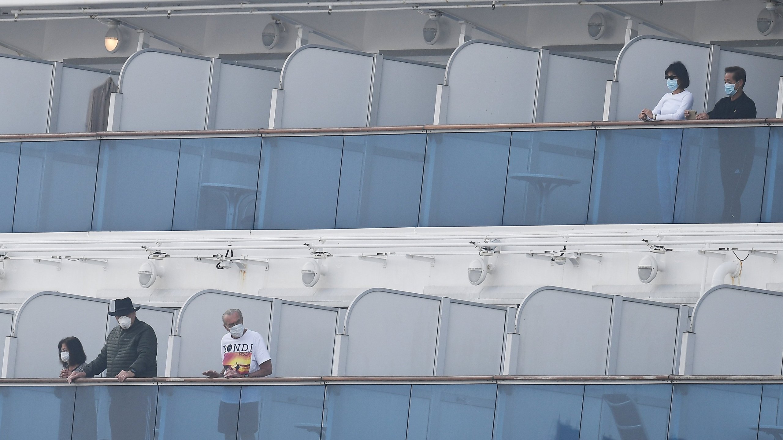 Passengers walk along the deck of the Diamond Princess cruise ship, with around 3,600 people quarantined onboard due to fears of the new COVID-19 coronavirus, at the Daikoku Pier Cruise Terminal in Yokohama on Feb. 14, 2020. (Credit: CHARLY TRIBALLEAU/AFP via Getty Images)