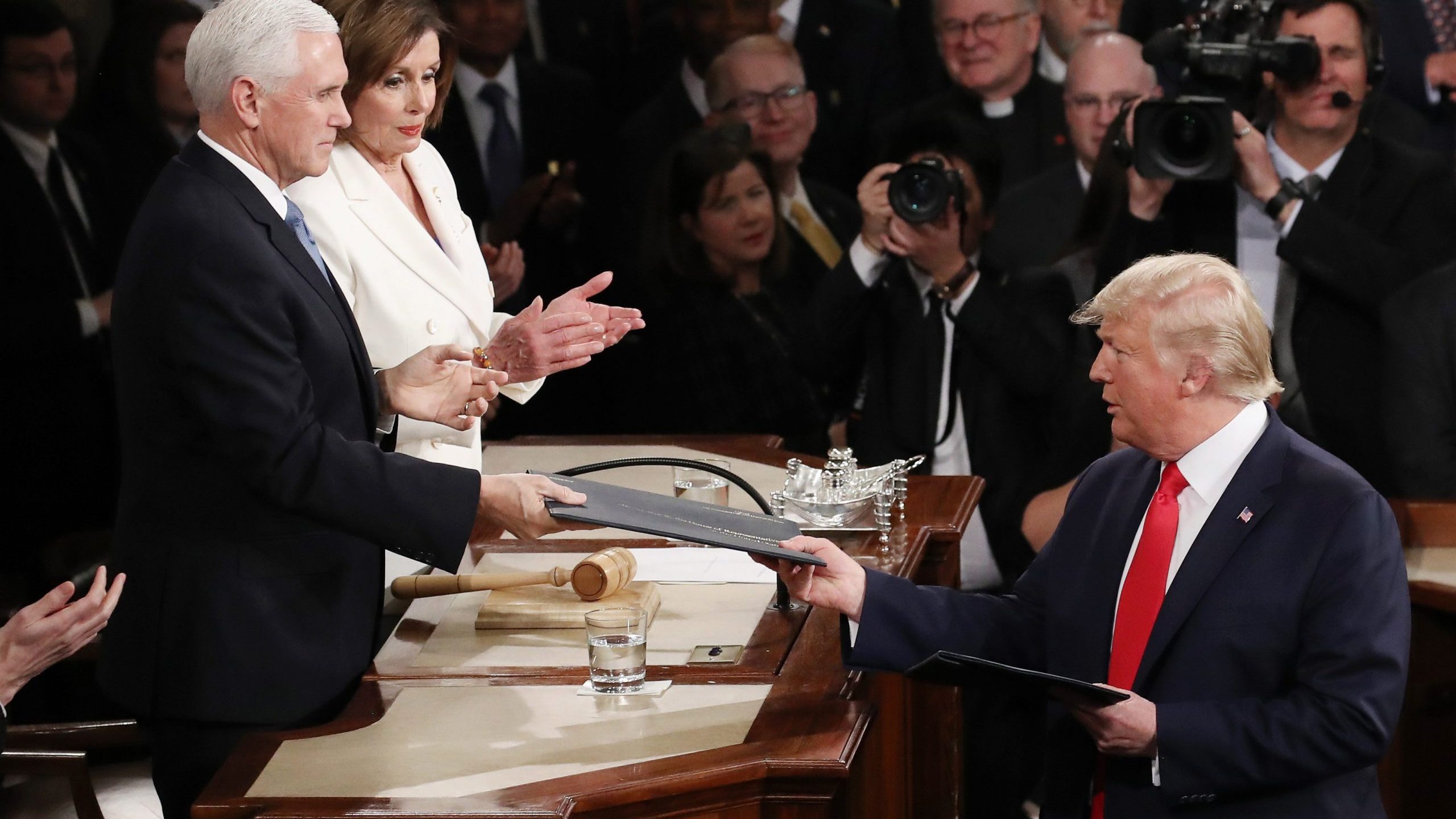 President Donald Trump hands Vice President Mike Pence a copy of his State of the Union speech before the address on Feb. 4, 2020. (Credit: Drew Angerer / Getty Images)