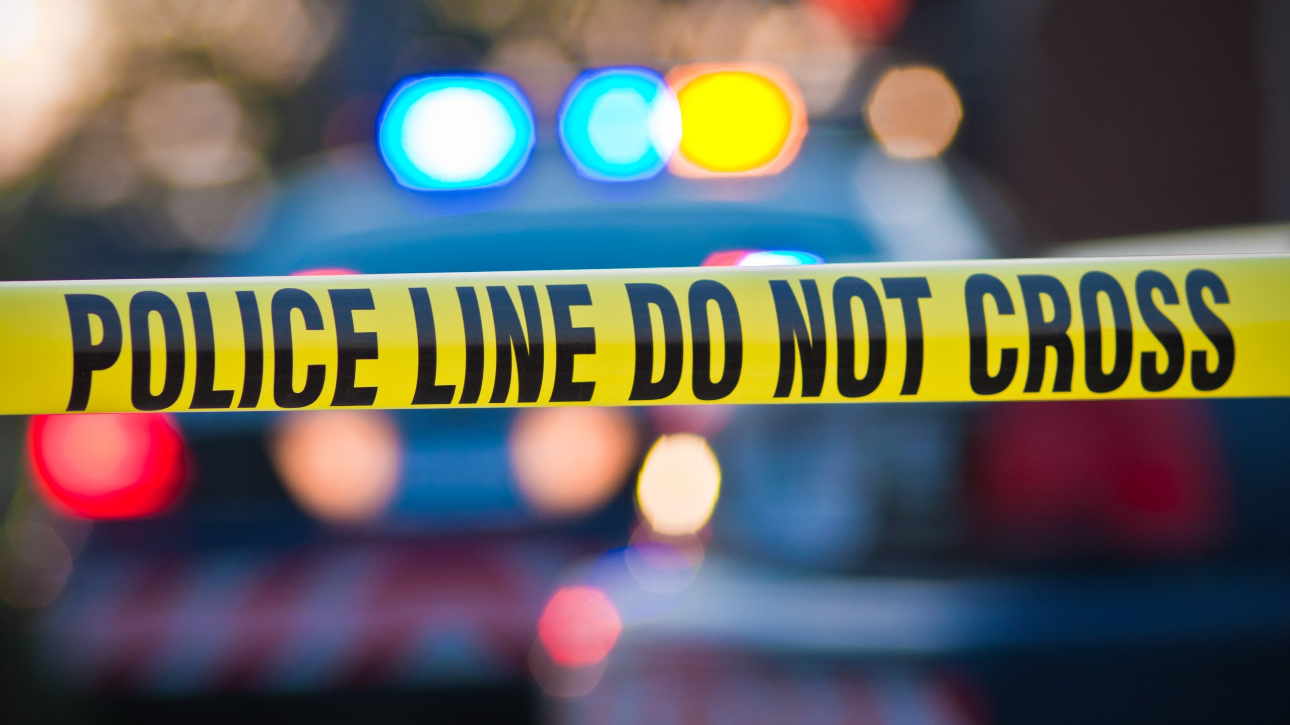 Yellow law enforcement line with police car and lights in the background is seen in this file photo. (Credit: Getty Images)