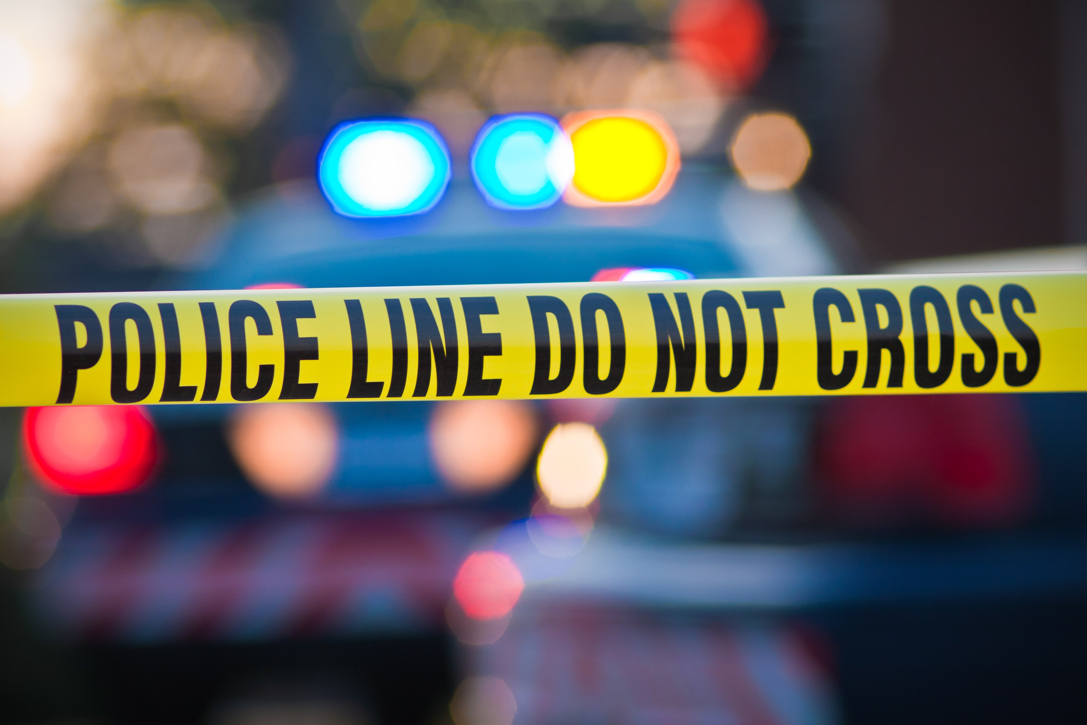 Yellow law enforcement line with police car and lights in the background is seen in this file photo. (Credit: Getty Images)