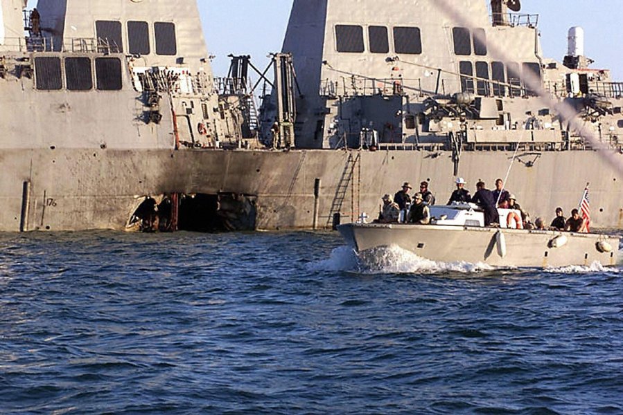 This US Navy file photo shows security personnel patrolling past the damaged USS Cole 18 October 2000 following the 12 October 2000 terrorist bombing attack on the ship in Aden, Yemen. (Credit: LYLE G. BECKER/AFP via Getty Images)