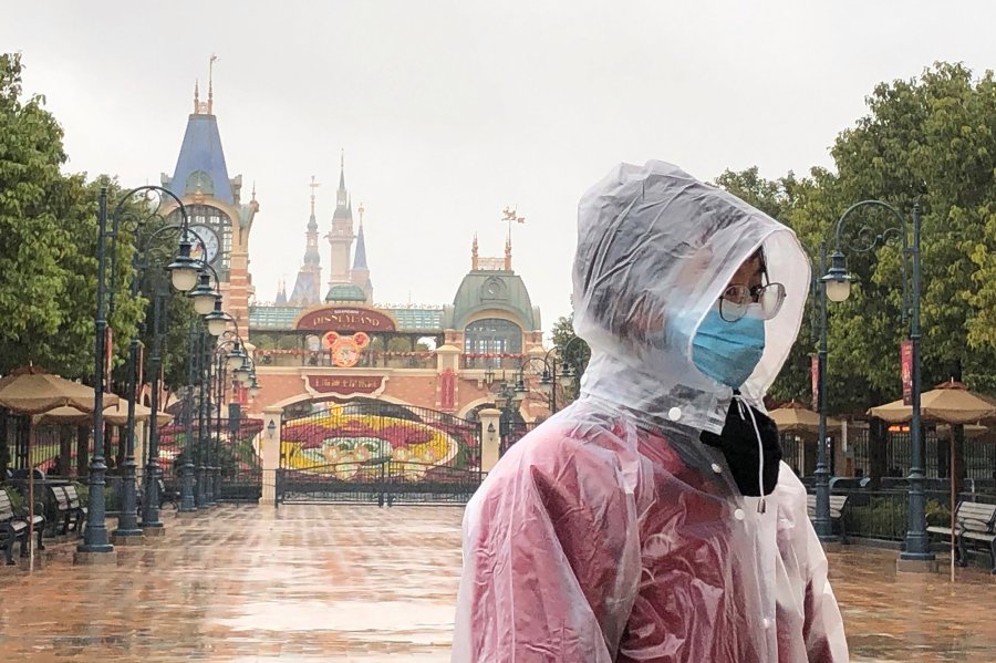 A Disney employee stands in front of the gates of the Shanghai Disney Resort. (Credit: Fut Ting/AP/Shutterstock via CNN Wire)