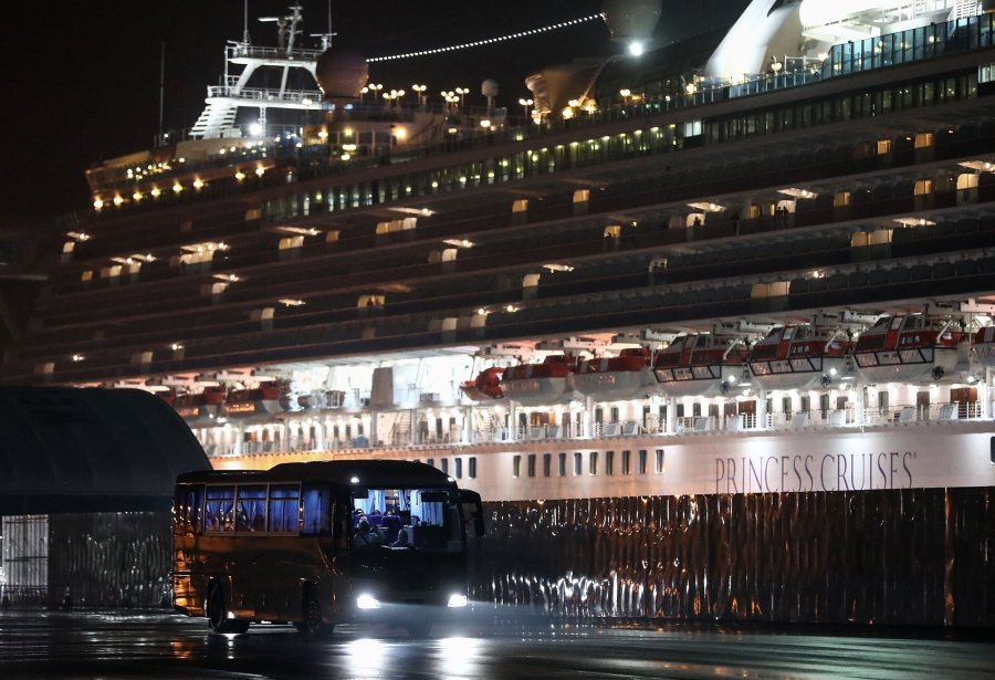 A bus carrying U.S. citizens leaves the Daikaku Pier Cruise Terminal in Yokohama port, next to the Diamond Princess cruise ship, with people quarantined onboard due to fears of the new COVID-19 coronavirus, on Feb. 17, 2020. (Credit: Behrouz Mehri/AFP/Getty Images)