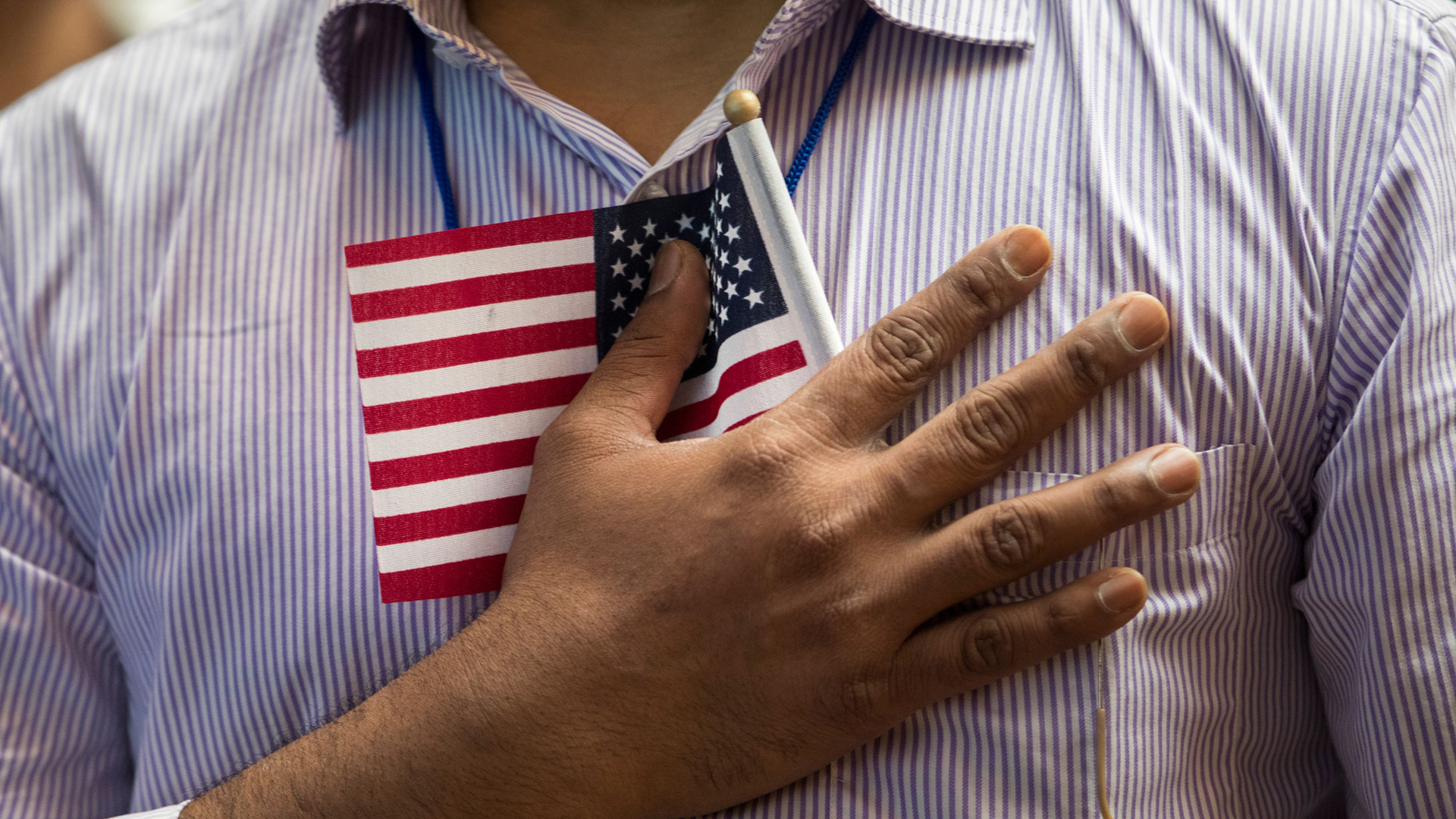 A new U.S. citizen holds a flag to his chest during the Pledge of Allegiance during a naturalization ceremony at the New York Public Library, July 3, 2018, in New York City. (Drew Angerer/Getty Images)