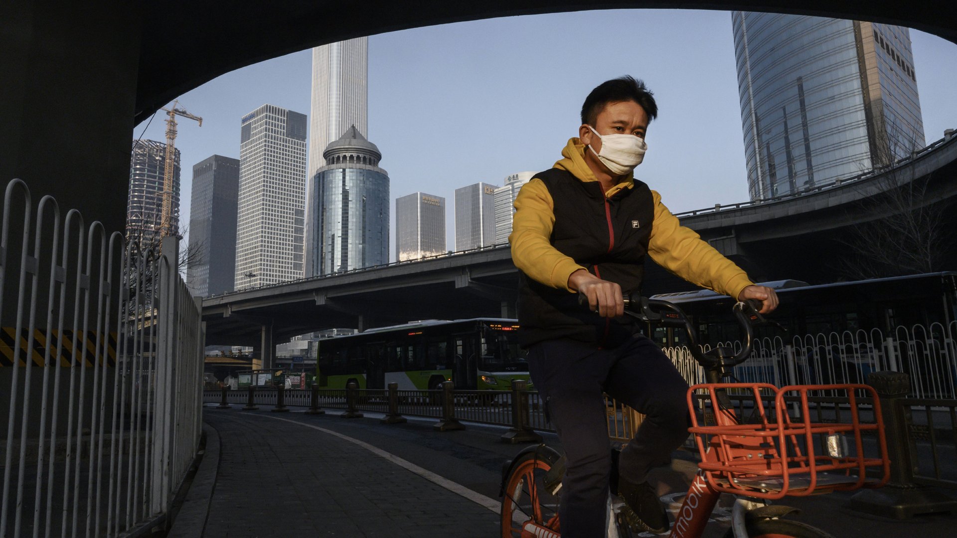 A Chinese man wears a protective mask as he cycles on a quiet road during the usual rush hour period on February 10, 2020 in Beijing, China. (Credit: Kevin Frayer/Getty Images)