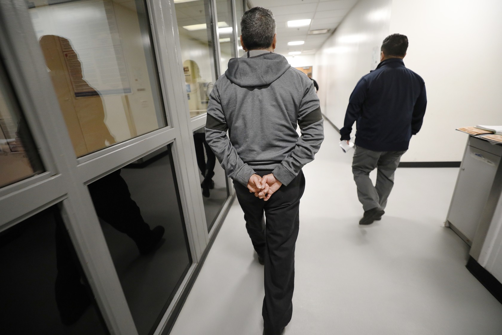 Marco Correa, center, is escorted by detention officers at the Enforcement and Removal operation Processing Center in downtown Los Angeles on March 16, 2020. (Al Seib/Los Angeles Times)