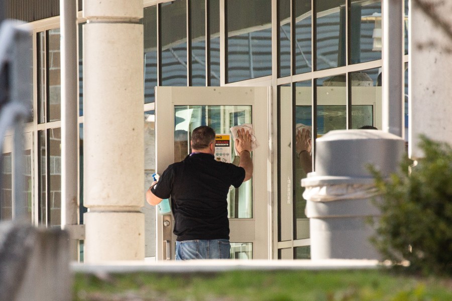 A staff member cleans a door at Bothell High School on Feb. 27, 2020, in Bothell, Washington. School district officials decided to close the school for disinfecting after a family member of a school staffer was quarantined for possible coronavirus. (David Ryder/Getty Images)