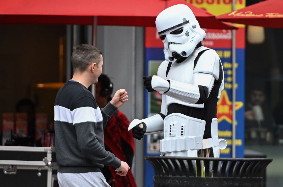 A person in a Stormtrooper costume who poses for snapshots with tourists in exchange for tips fist bumps with a passerby, on the Hollywood Boulevard on March 10, 2020. Fist bumps are being encouraged by health officials to avoid the spread of COVID-19. (ROBYN BECK/AFP via Getty Images)