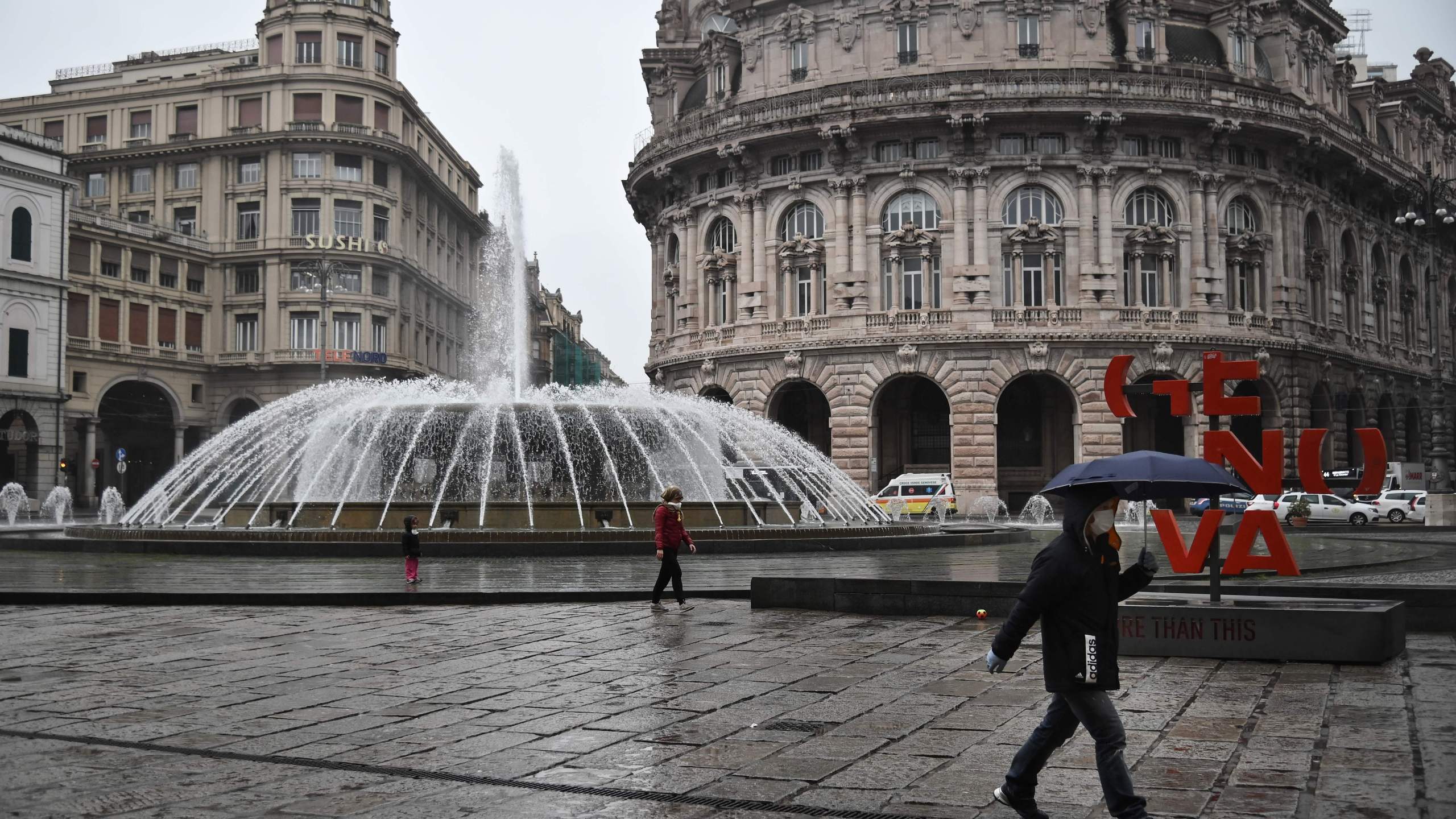 People wearing a protection mask walk across Piazza Raffaele de Ferrari in Genoa, Liguria, on March 13, 2020. (MARCO BERTORELLO/AFP via Getty Images)