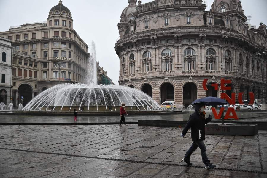 People wearing a protection mask walk across Piazza Raffaele de Ferrari in Genoa, Liguria, on March 13, 2020. (MARCO BERTORELLO/AFP via Getty Images)