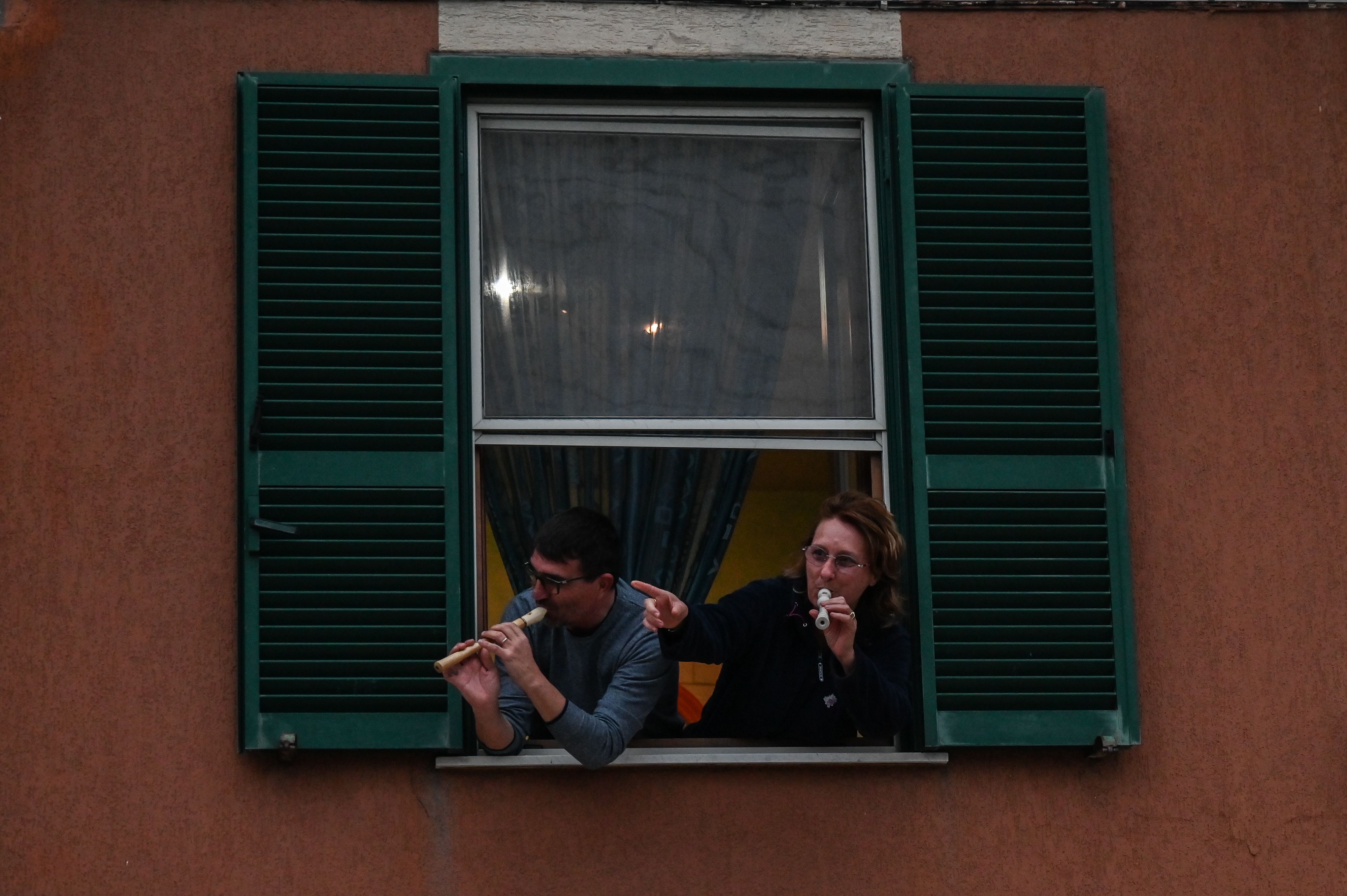 People play the Italian national anthem with from the window of their house in Rome during a music flash mob aimed at livening up the city's silence during the coronavirus lockdown, on March 13, 2020. (Credit: Andreas Solaro / AFP / Getty Images)