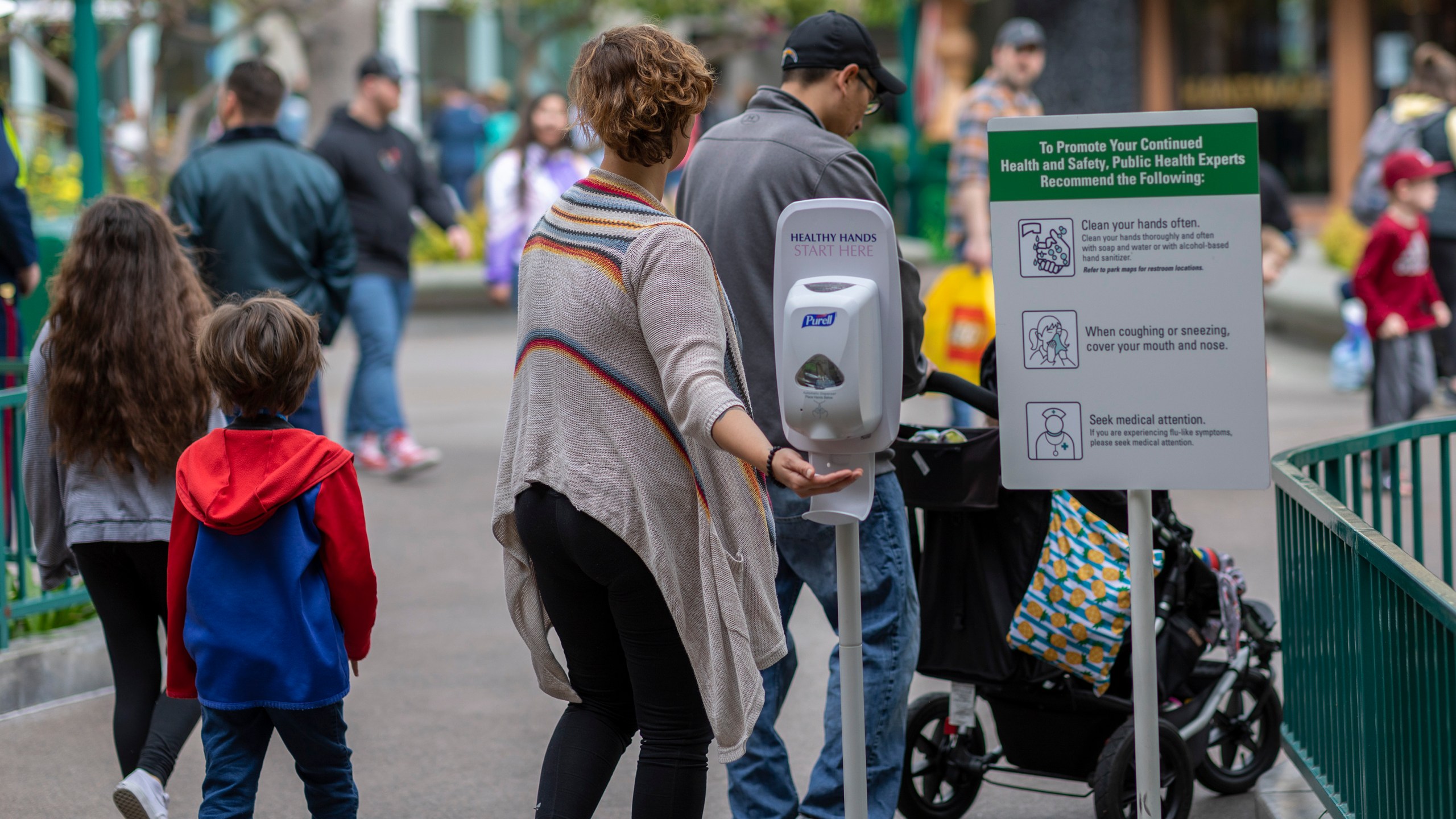 A woman reaches for hand sanitizer in Downtown Disney, which remains open on the first day of the closure of Disneyland and Disney California Adventure theme parks as fear of the spread of coronavirus continue on March 14, 2020. (Credit: David McNew / AFP / Getty Images)