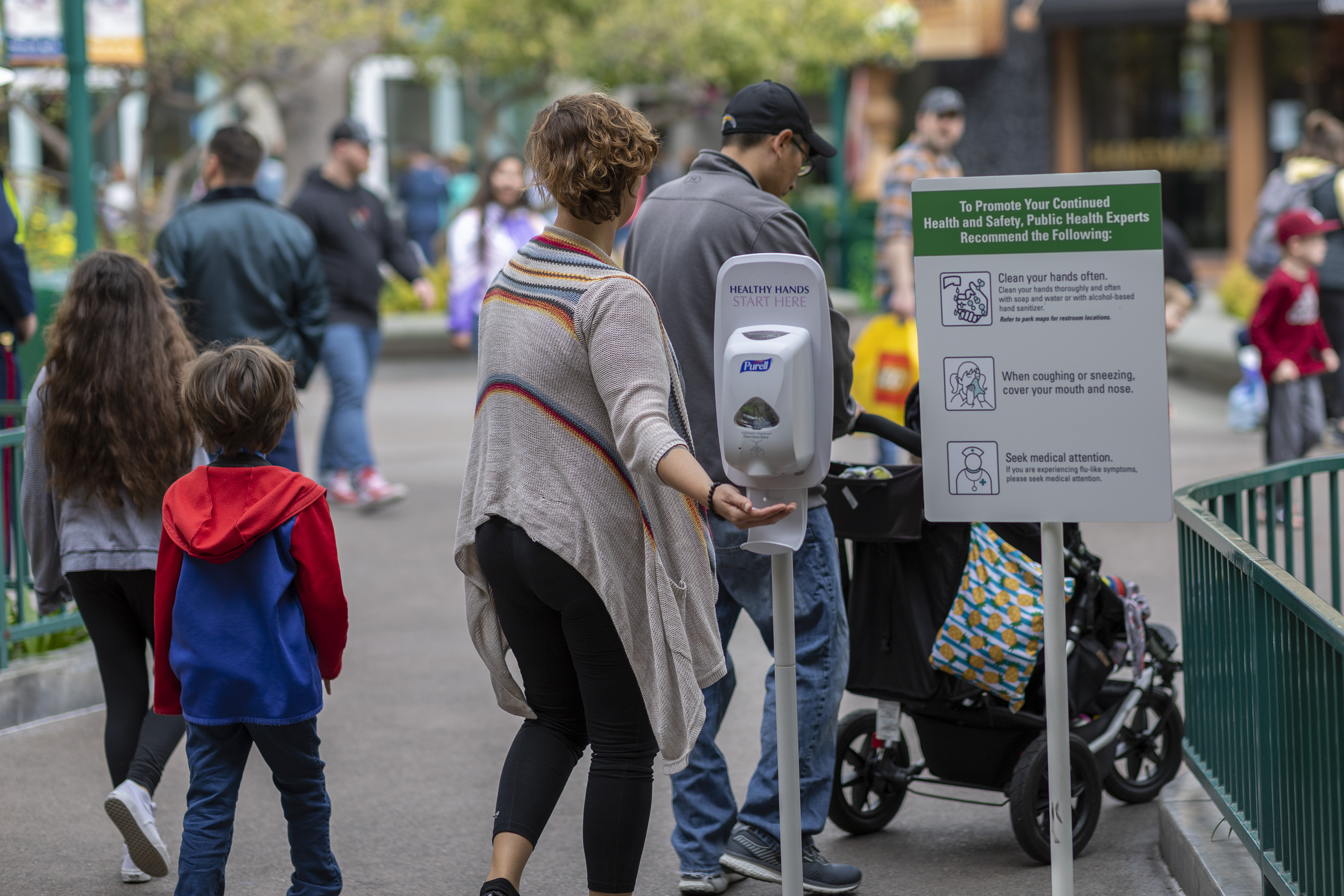 A woman reaches for hand sanitizer in Downtown Disney, which remains open on the first day of the closure of Disneyland and Disney California Adventure theme parks as fear of the spread of coronavirus continue on March 14, 2020. (Credit: David McNew / AFP / Getty Images)