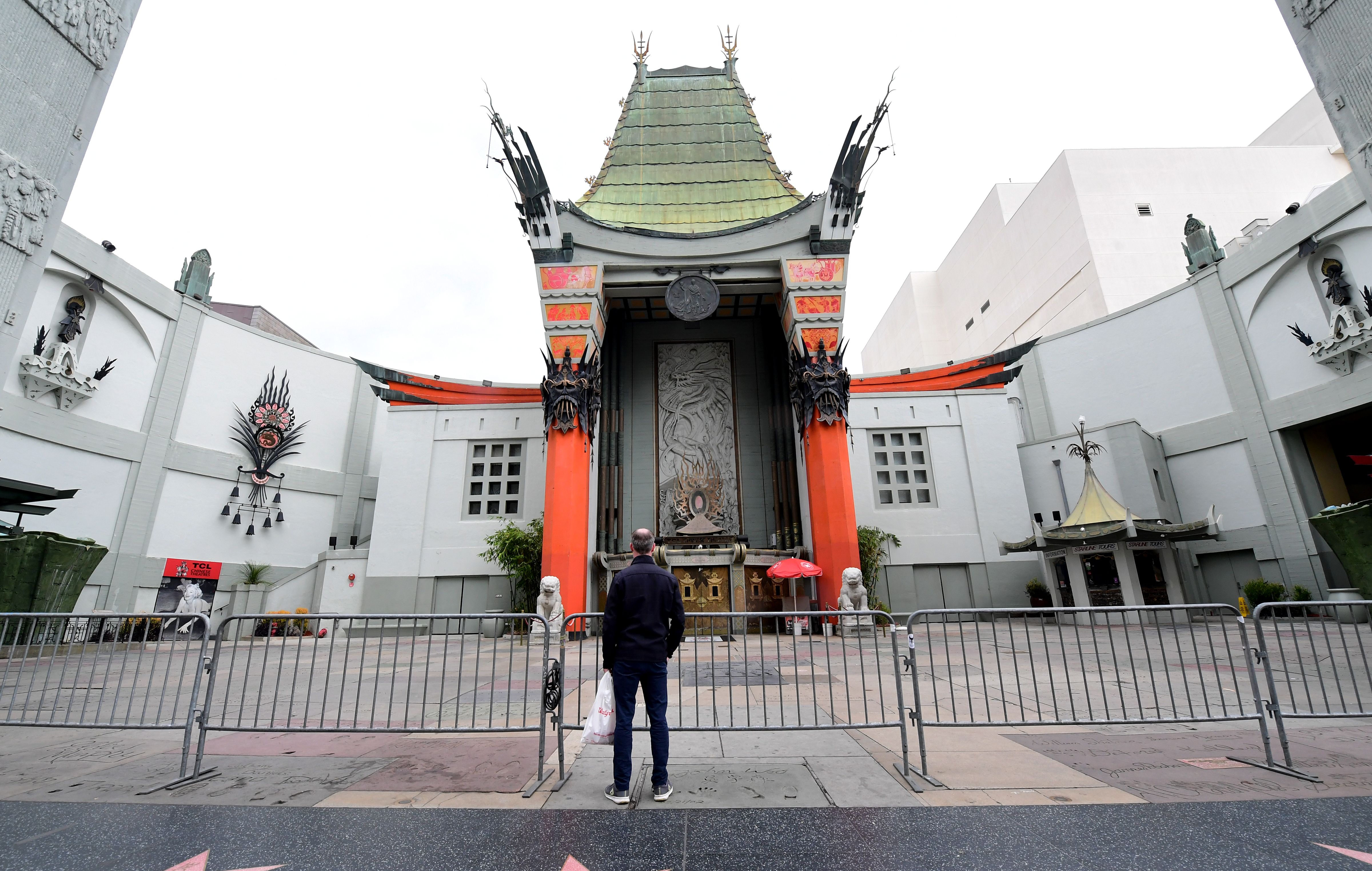 A man stands behind barricades in front of a temporarily closed TCL Chinese Theater in Hollywood on March 16, 2020, as the Coronavirus pandemic brings much of California to a standstill. (FREDERIC J. BROWN/AFP via Getty Images)