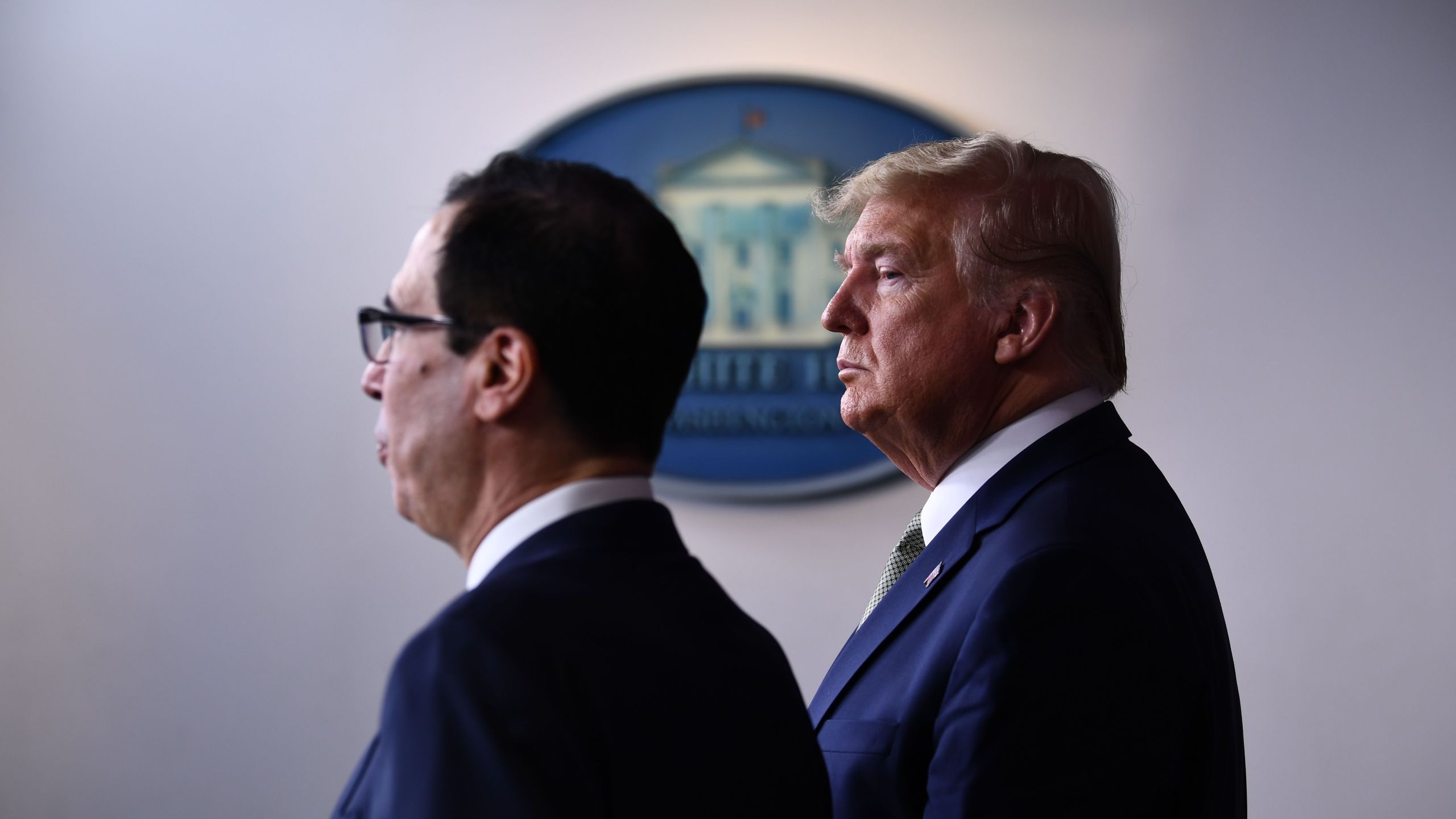 Donald Trump listens as Treasury Secretary Steven Mnuchin speaks during the daily press briefing on the Coronavirus pandemic situation at the White House on March 17, 2020 in Washington, D.C. (BRENDAN SMIALOWSKI/AFP via Getty Images)