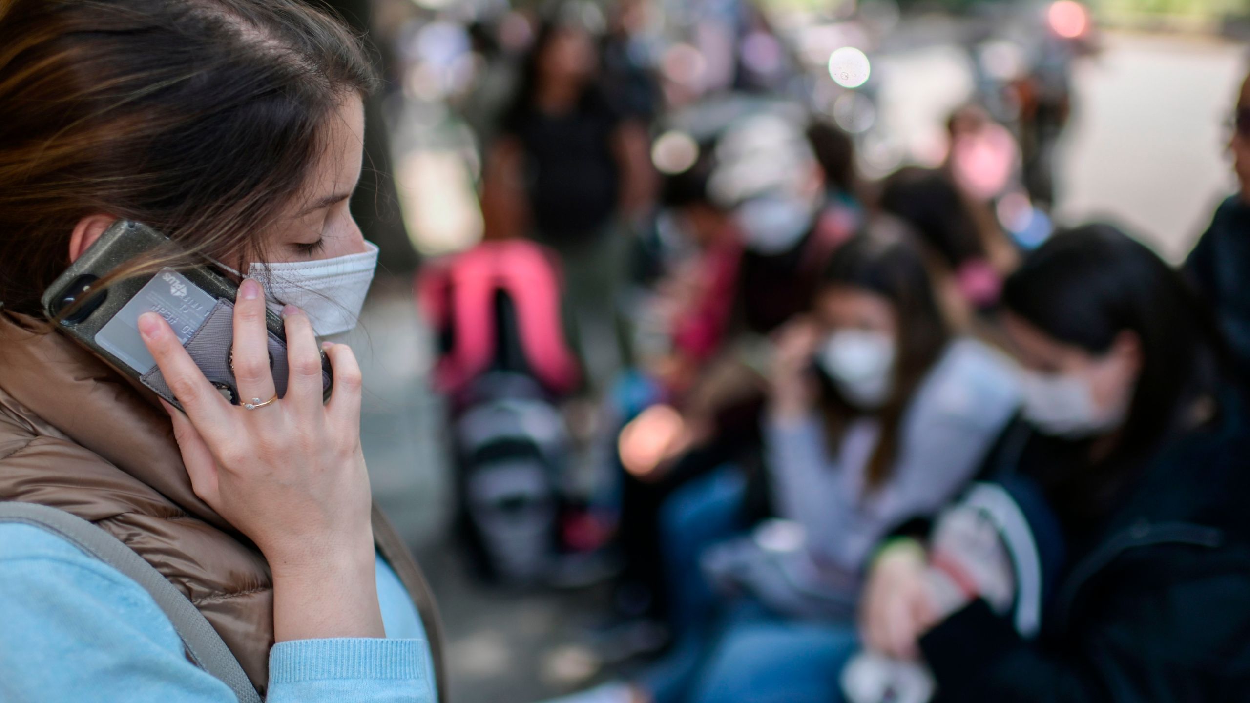 A woman wearing a face mask speaks on her mobile phone as she waits outside the consulate of Peru in Mexico City, on March 18, 2020. (Pedro Pardo/AFP via Getty Images)