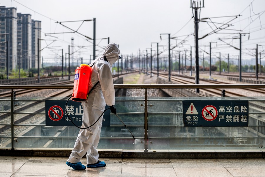 A crew member sprays disinfectant at Wuhan Railway Station in Wuhan in China's central Hubei province on March 24, 2020. (STR/AFP via Getty Images)