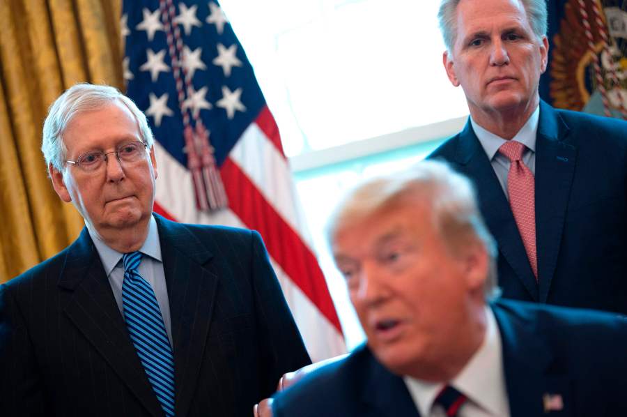 U.S. Senate Majority Leader Mitch McConnell (L) and House Minority Leader Kevin McCarthy (R) look on as U.S. President Donald Trump speaks before signing the CARES act, a $2 trillion rescue package to provide economic relief amid the coronavirus outbreak, at the Oval Office of the White House on March 27, 2020. (JIM WATSON/AFP via Getty Images)