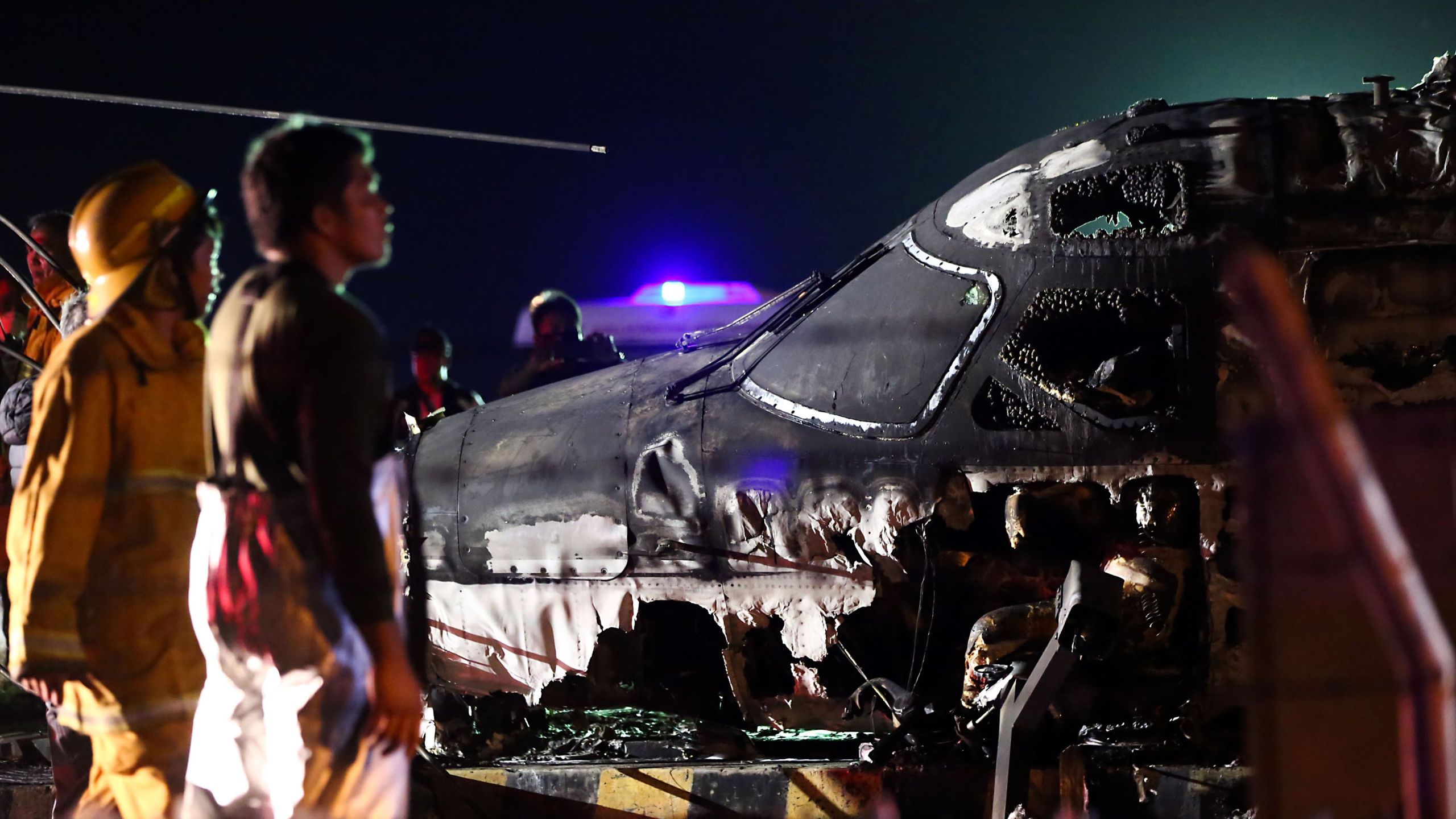 Rescuers stand next to the wreckage of a Westwind aircraft after it caught fire during takeoff at Manila International Airport in Manila on March 29, 2020. (AFP via Getty Images)