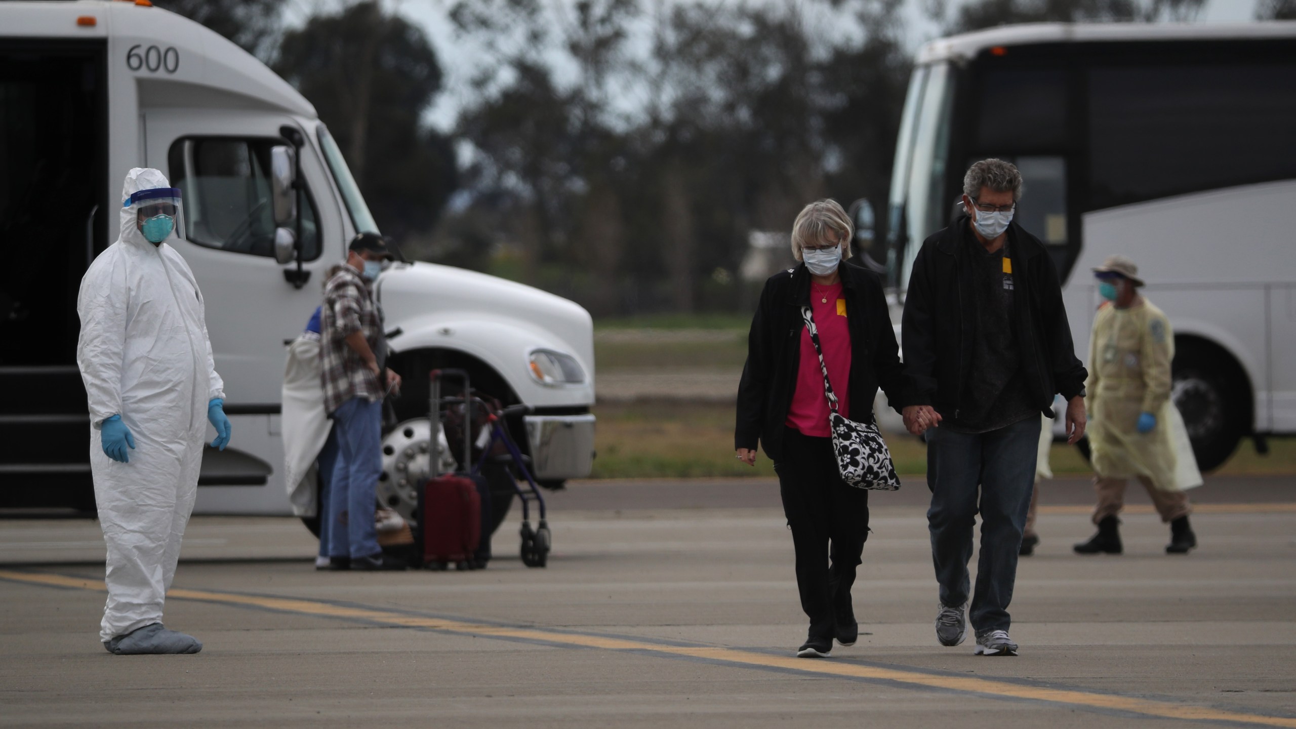 Passengers from the Grand Princess cruise ship walk across the tarmac before boarding a charter plane at Oakland International Airport on March 10, 2020, in Oakland. (Justin Sullivan/Getty Images)