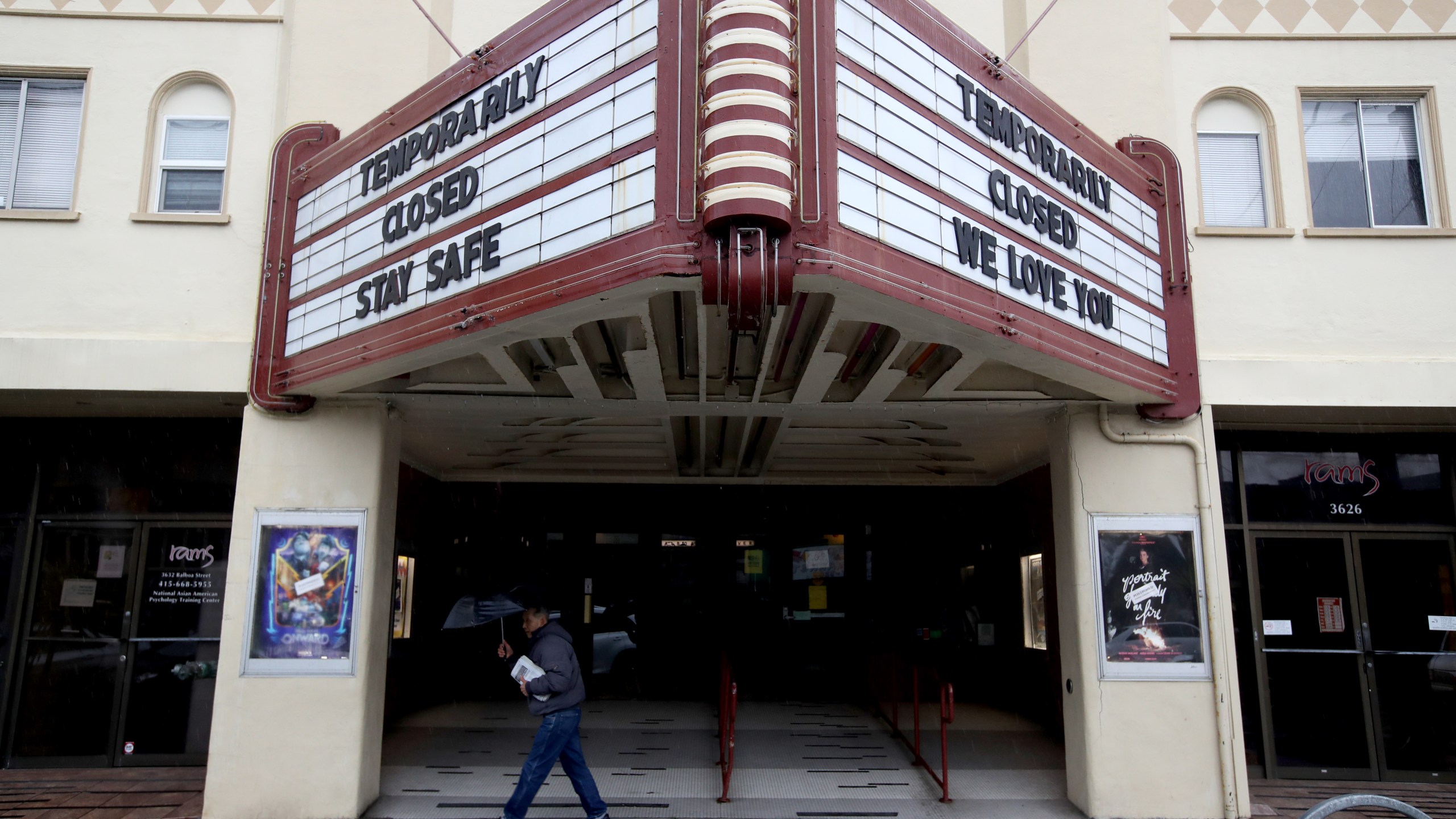 A pedestrian walks under the marquee at Balboa Theater that notes the theater is closed until further notice due to a statewide ordinance banning gatherings of more than 250 people on March 15, 2020 in San Francisco. (Justin Sullivan / Getty Images)