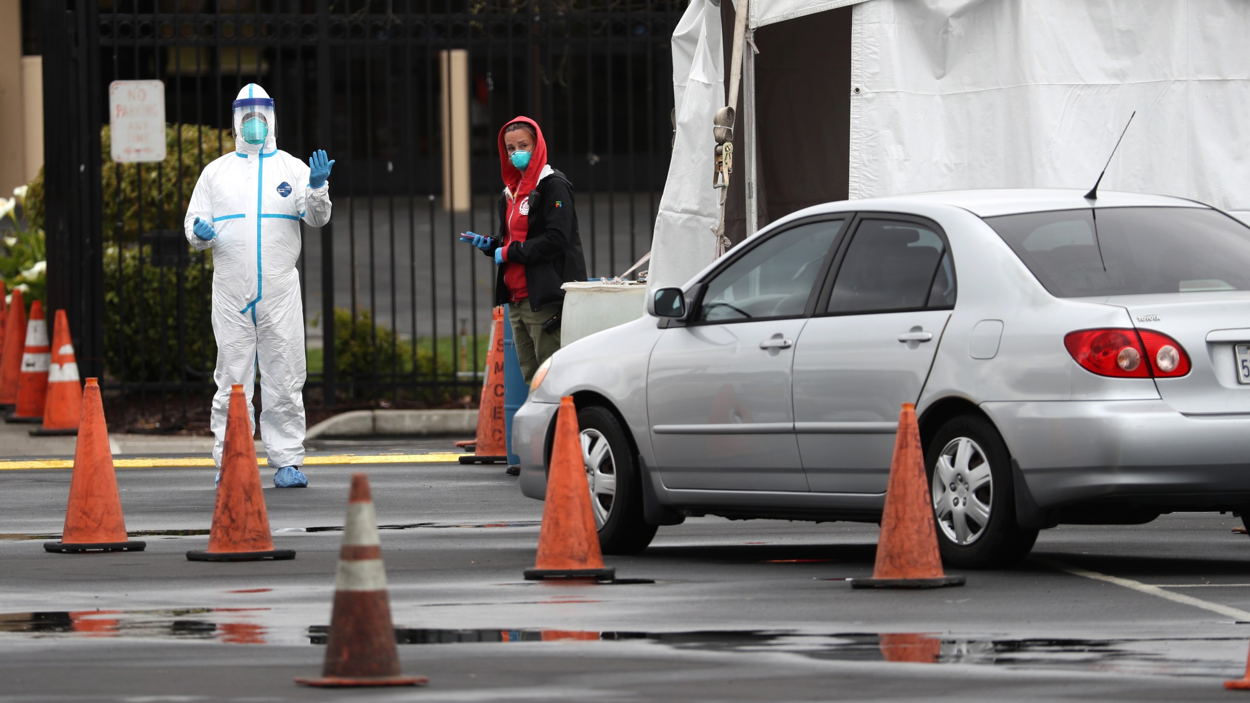 A medical worker guides a car that is going through a coronavirus drive-thru test clinic at the San Mateo County Event Center on March 16, 2020 in San Mateo, California. (Justin Sullivan/Getty Images)