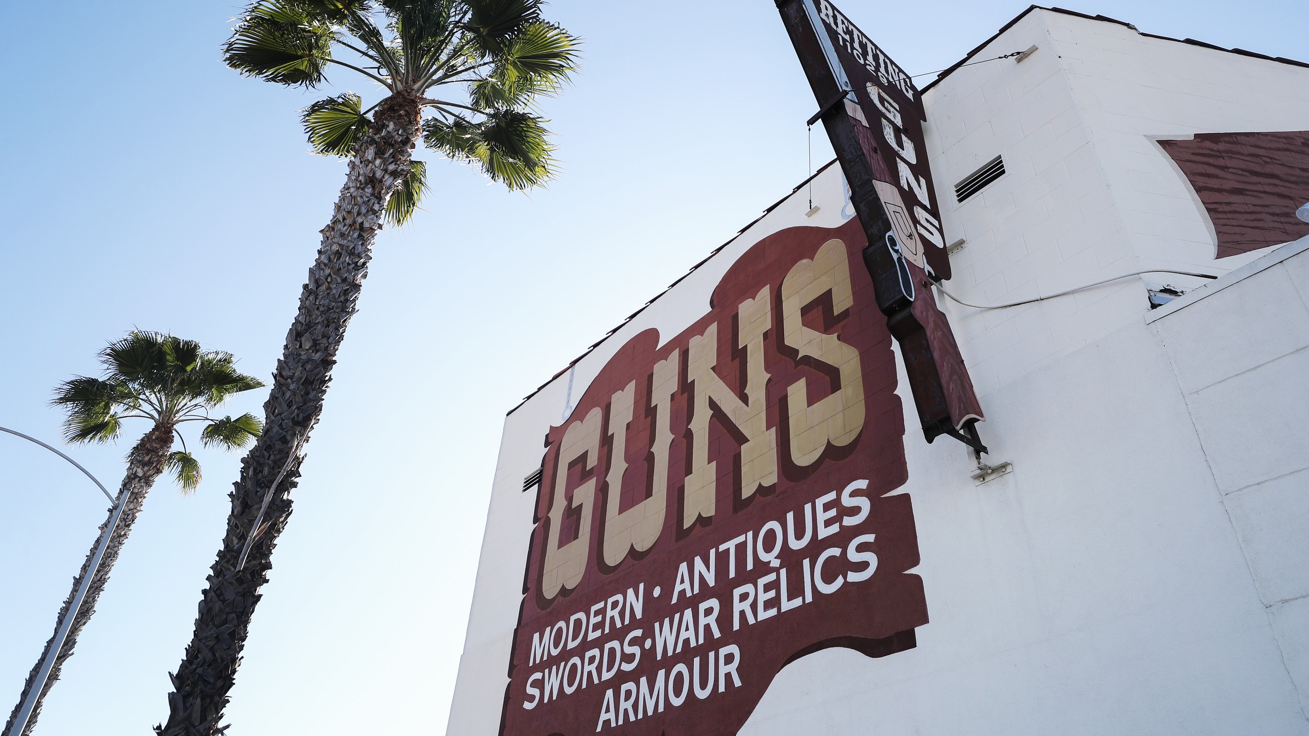 Palm trees stand next to the Martin B. Retting, Inc. guns store as the coronavirus pandemic continues on March 24, 2020, in Culver City. (Mario Tama/Getty Images)