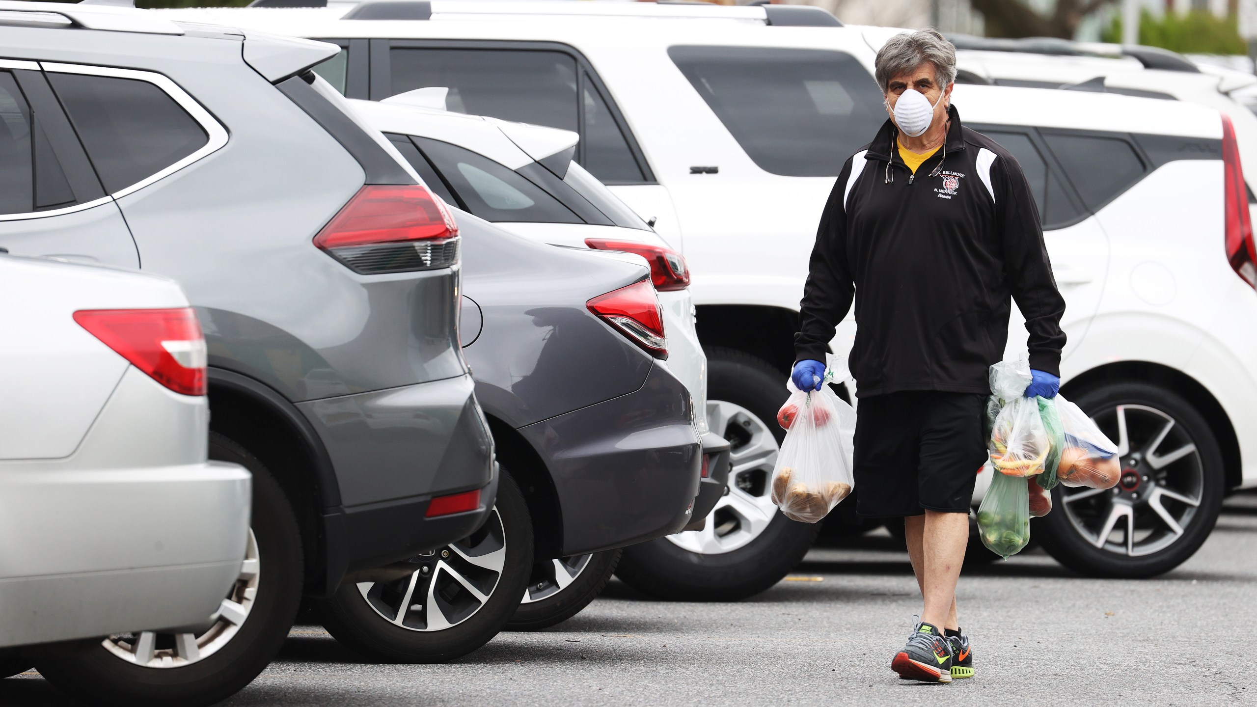 A shopper wear A shopper wearing a mask and gloves heads to his car after food shopping at Pat's Farms grocery store on March 31, 2020 in Merrick, New York. (Al Bello/Getty Images)ing a mask and gloves heads to his car after food shopping at Pat's Farms grocery store on March 31, 2020 in Merrick, New York. )Al Bello/Getty Images)