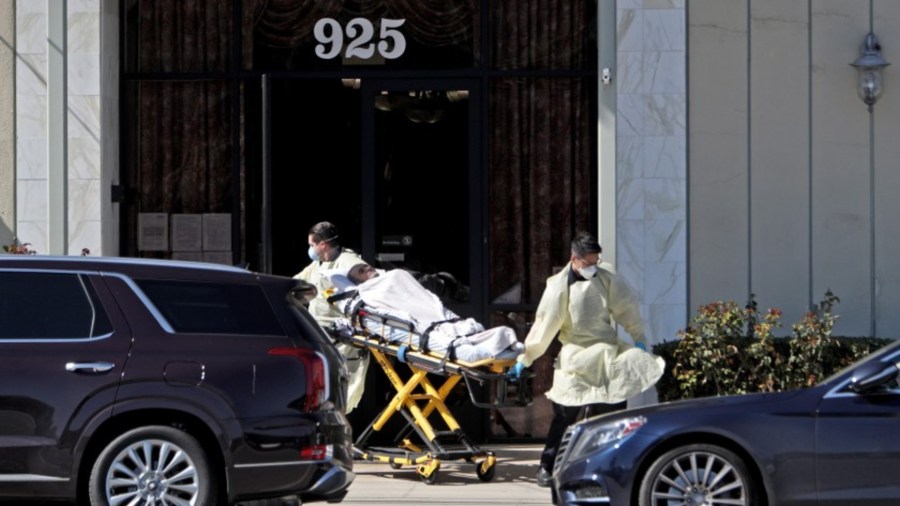 Ambulance emergency medical technicians pick up a patient, whose condition is unknown, from Alameda Care Center on West Alameda Avenue in Burbank on Friday. The center is reporting multiple positive cases of the novel coronavirus that causes COVID-19 among its senior residents. (Raul Roa/Burbank Leader via Los Angeles Times)