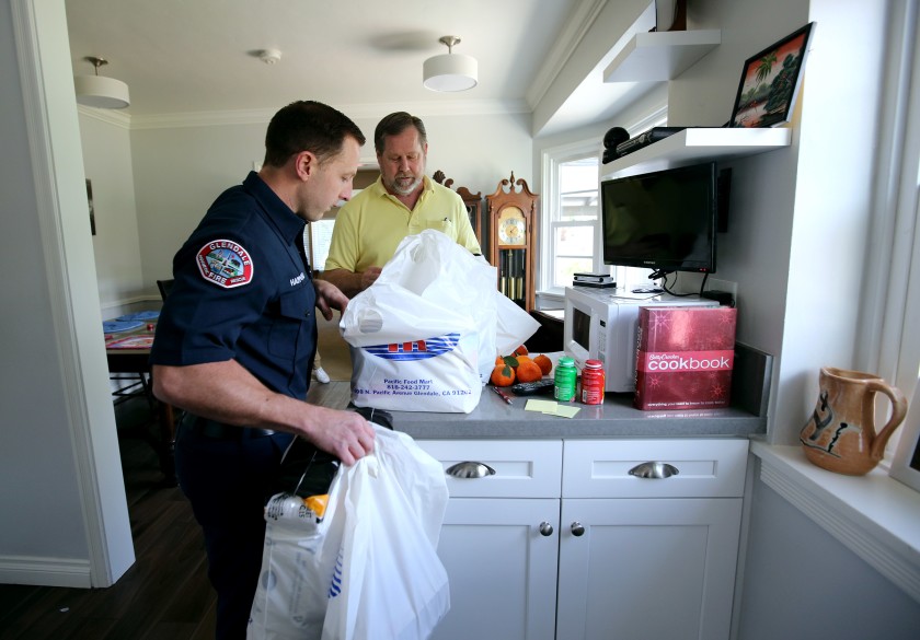 Glendale Firefighter-Paramedic Spencer Hammond delivers groceries to 64-year-old Jim Rohrig in this undated photo. (Credit: Raul Roa/Glendale News-Press)