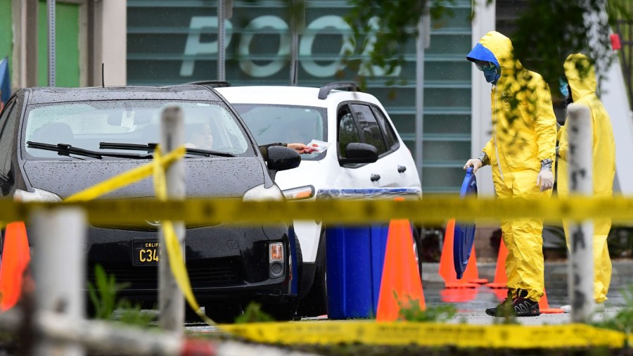 A driver in a vehicle drops his COVID-19 test into a bin at a coronavirus mobile testing site at Lincoln Park in Los Angeles, California on April 10, 2020 as COVID-19 antibody testing begins at undiscolsed locations across Los Angeles County (Frederic J. Brown/AFP/Getty Images)