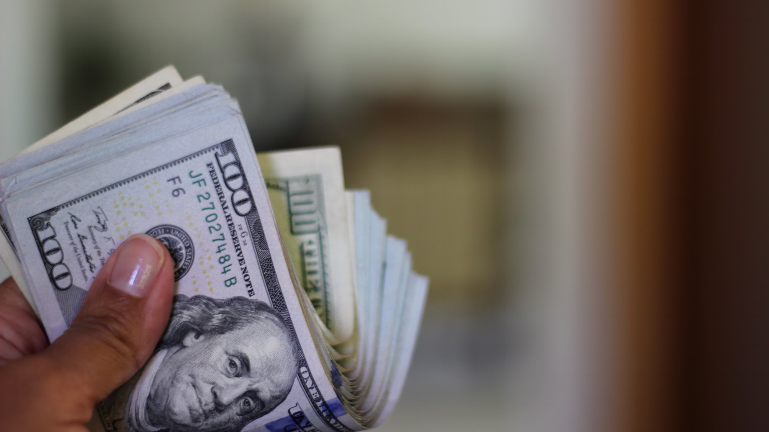 A person holds a wad of hundred dollar bills. (Getty Images)