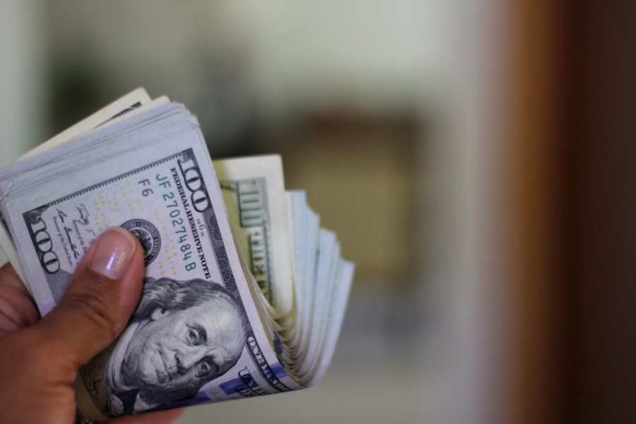 A person holds a wad of hundred dollar bills. (Getty Images)