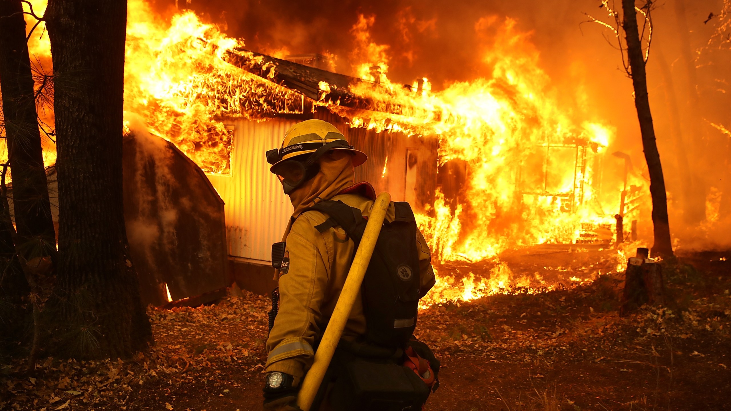 A Cal Fire firefighter is seen outside a burning home as the Camp Fire moves through the area on Nov. 9, 2018, in Magalia, California. (Justin Sullivan/Getty Images)