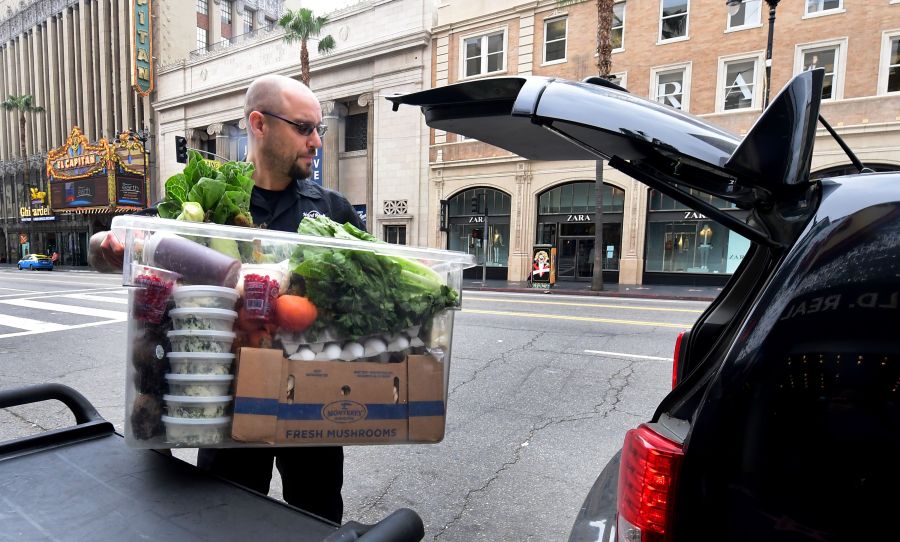 Jameson Carbonneau loads of carton of cooked meals from the Hard Rock Cafe in Hollywood, California for delivery on March 16, 2020 as the Coronavirus pandemic brings much of California to a standstill. (FREDERIC J. BROWN/AFP via Getty Images)