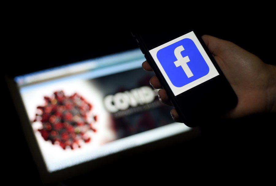 The Facebook logo is displayed on a mobile phone screen photographed in front of a coronavirus COVID-19 illustration on a computer screen on March 25, 2020 in Arlington, Virg. (OLIVIER DOULIERY/AFP via Getty Images)