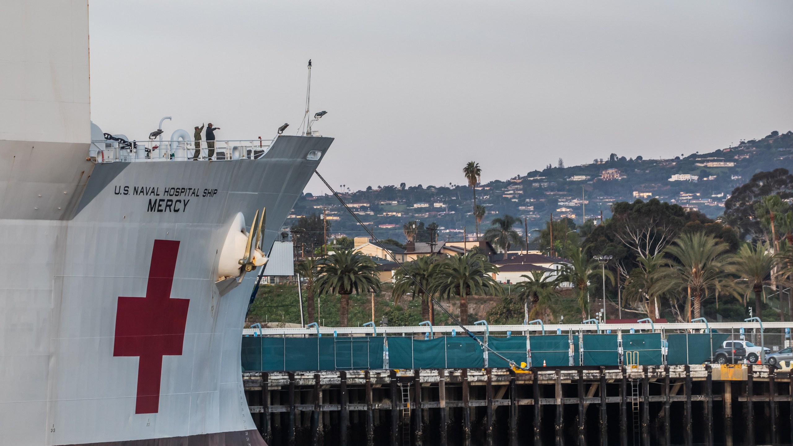 Military personnel of the USNS Mercy wave after the ship docked at the Port of Los Angeles on March 28, 2020. (Credit: Apu Gomes / AFP / Getty Images)