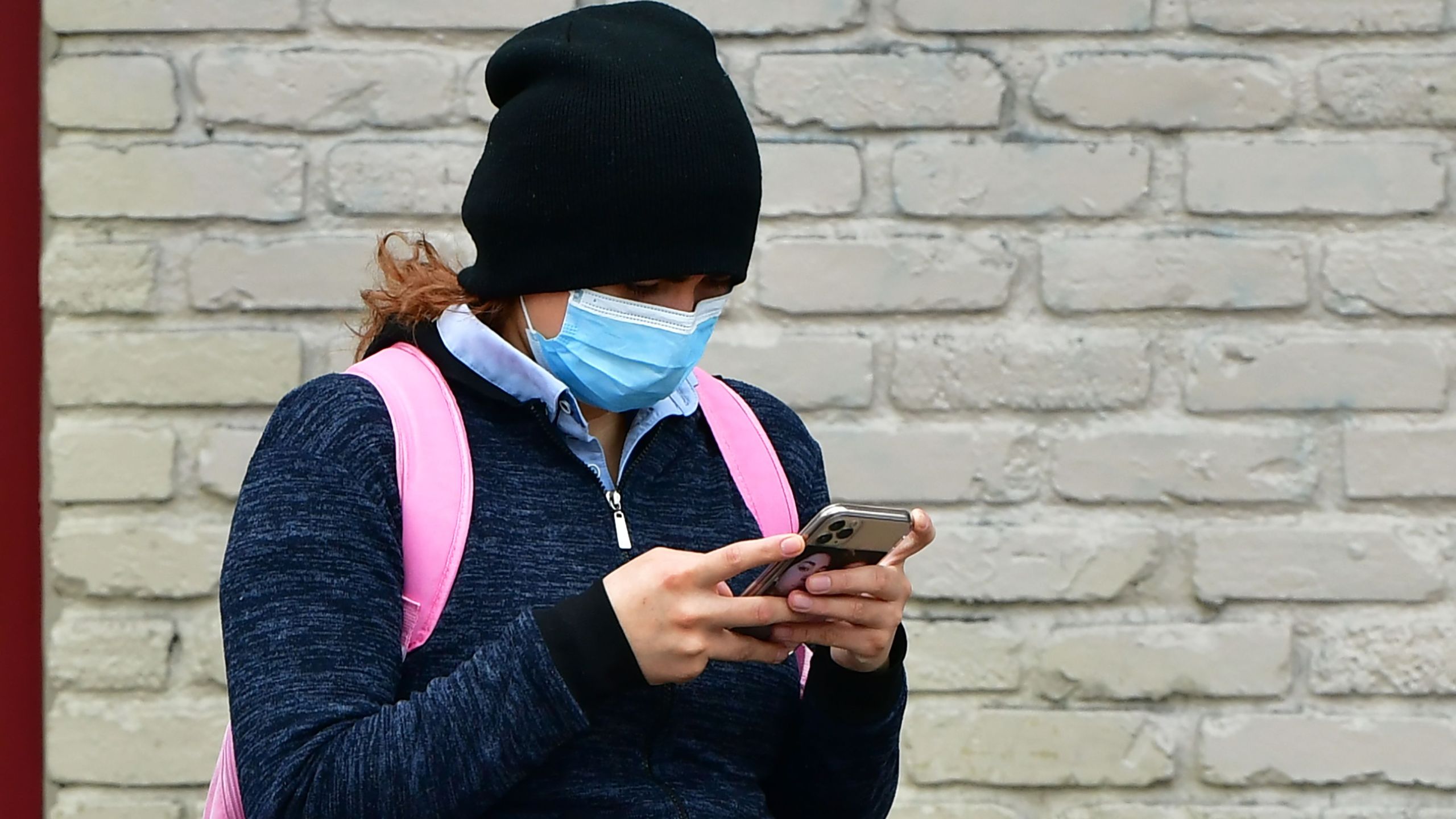 A woman wears a face mask while checking her cellphone in Los Angeles on April 6, 2020. (Frederic J. Brown / AFP / Getty Images)