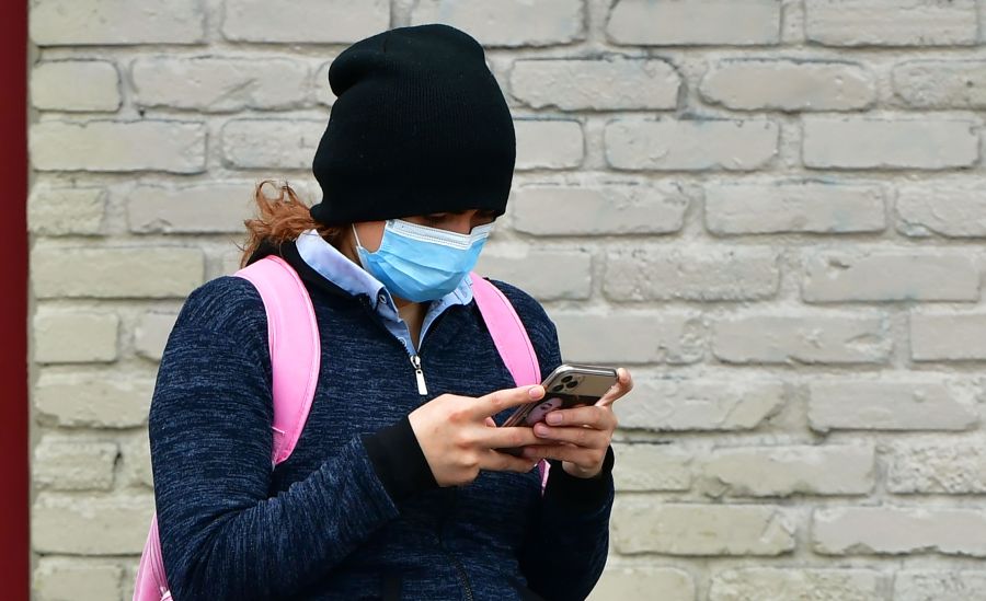 A woman wears a face mask while checking her cellphone in Los Angeles on April 6, 2020. (Frederic J. Brown / AFP / Getty Images)