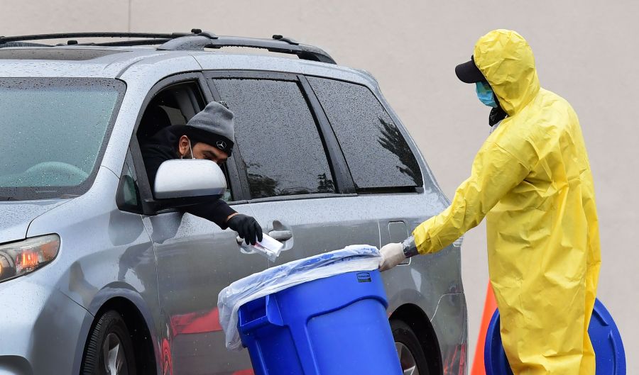 A driver drops his COVID-19 test into a bin at a coronavirus mobile testing site at Lincoln Park in Los Angeles on April 10, 2020. (Credit: Frederic J. Brown / AFP / Getty Images)