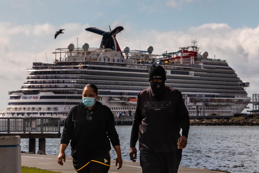 A couple wearing face masks as a preventive measure against the spread of the COVID-19 walk at the Marina Long Beach with Cruise Ships docked at the port due to a no-sail order in Long Beach. (Apu Gomes/AFP via Getty Images)