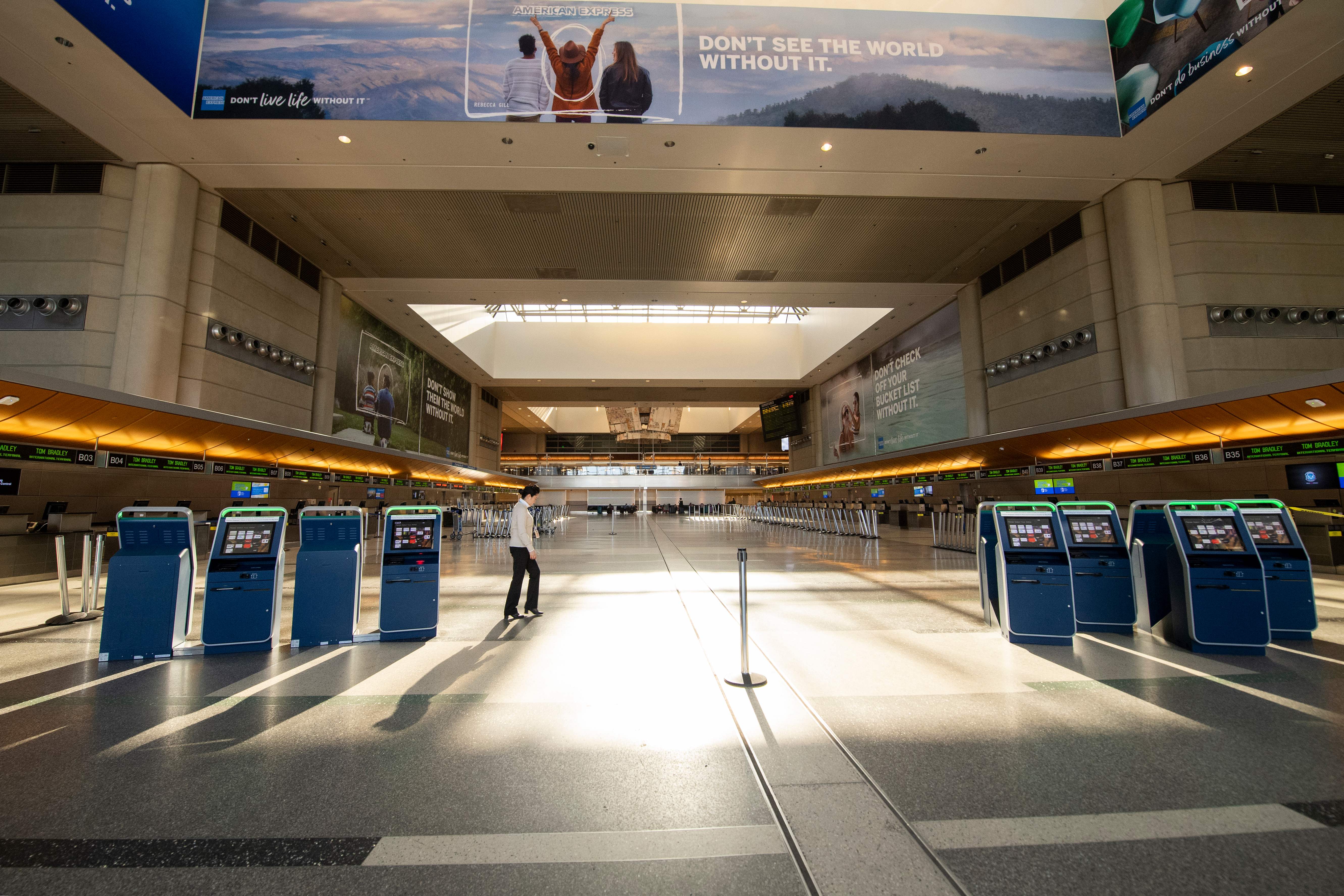 A woman walks through an empty Tom Bradley Terminal at Los Angeles International Airport on April 16, 2020, in Los Angeles. (VALERIE MACON/AFP via Getty Images)