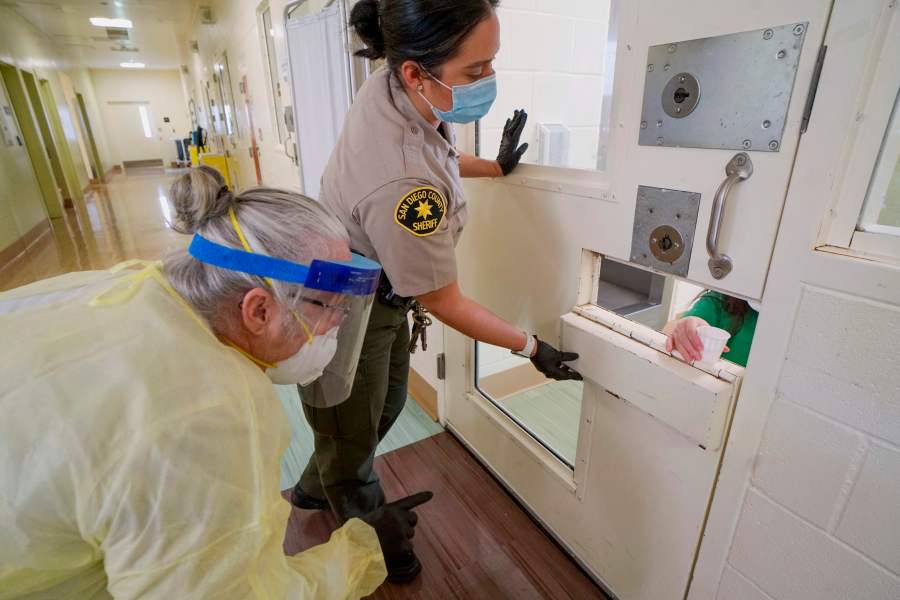 A Sheriff's deputy and an on-site nurse give medications to an inmate at Las Colinas Women's Detention Facility in Santee, California, on April 22, 2020. (Sandy Huffaker/ AFP via Getty Images)