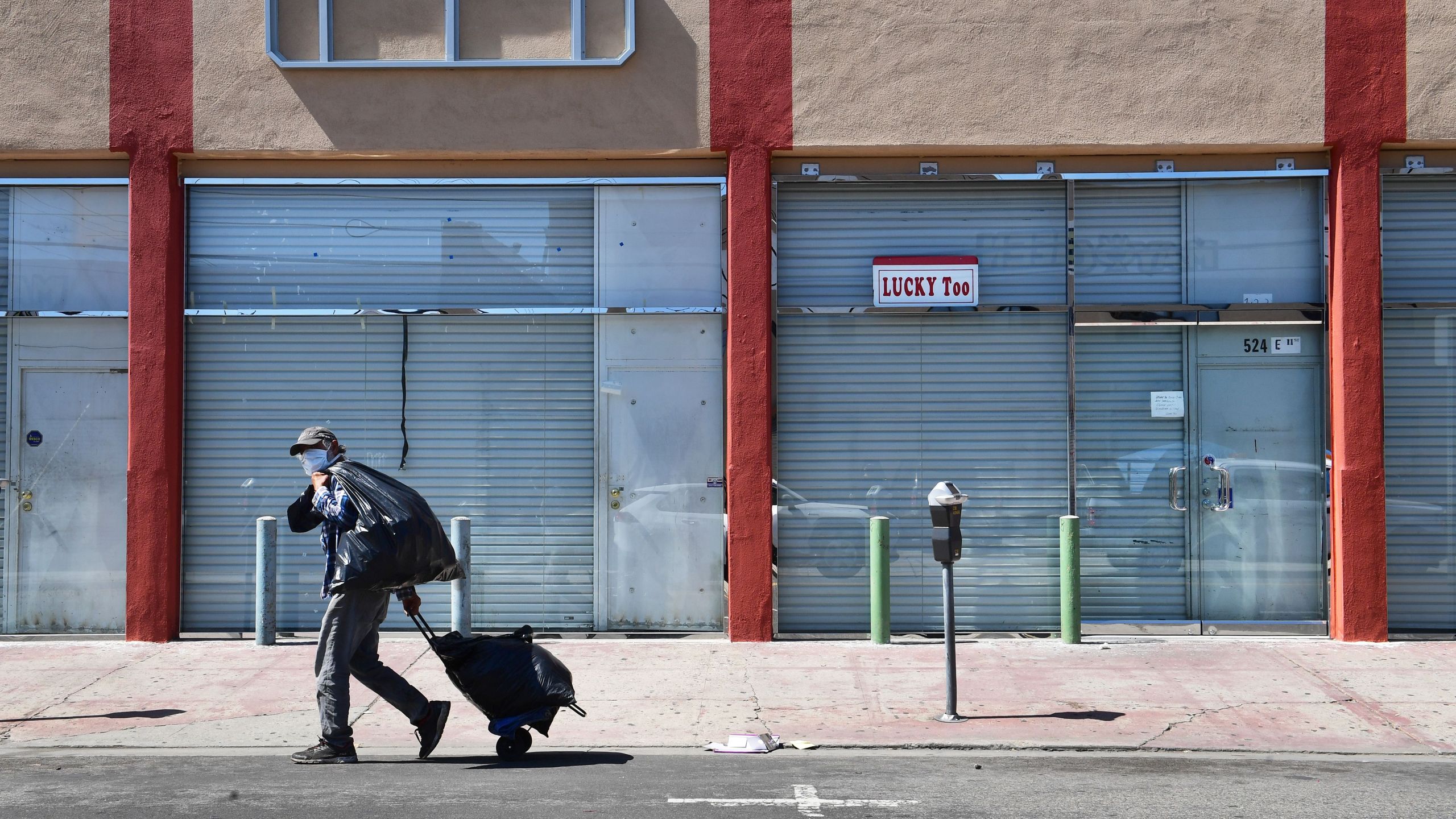 A man in a face mask walks past closed shopfronts in the Fashion District in Downtown Los Angeles, California on April 22, 2020, amid the novel coronavirus pandemic. More than 50% of Angelenos are now unemployed, according to a national survey. (FREDERIC J. BROWN/AFP via Getty Images)